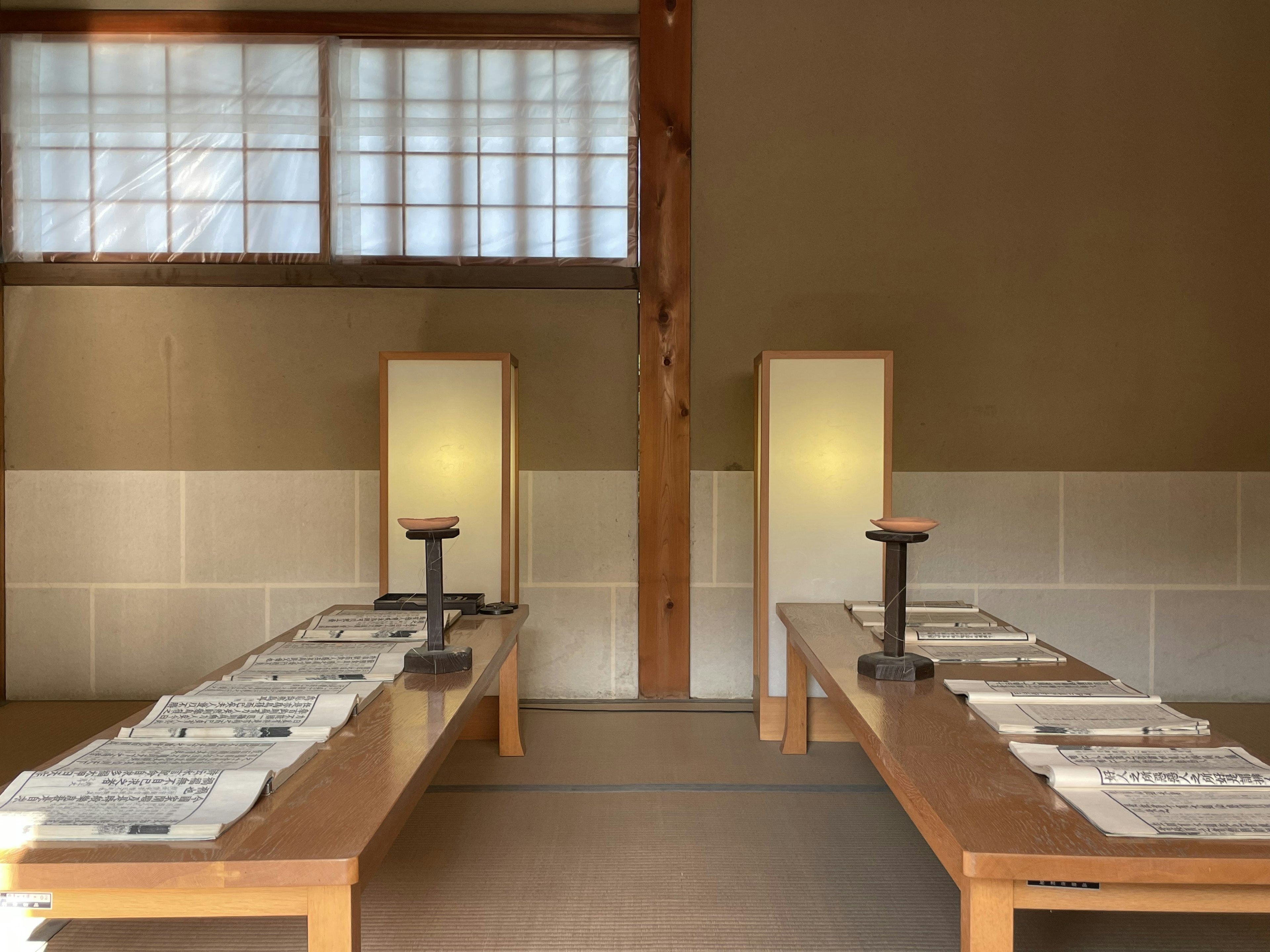 Interior de una habitación japonesa tradicional con mesas de madera, periódicos y lámparas