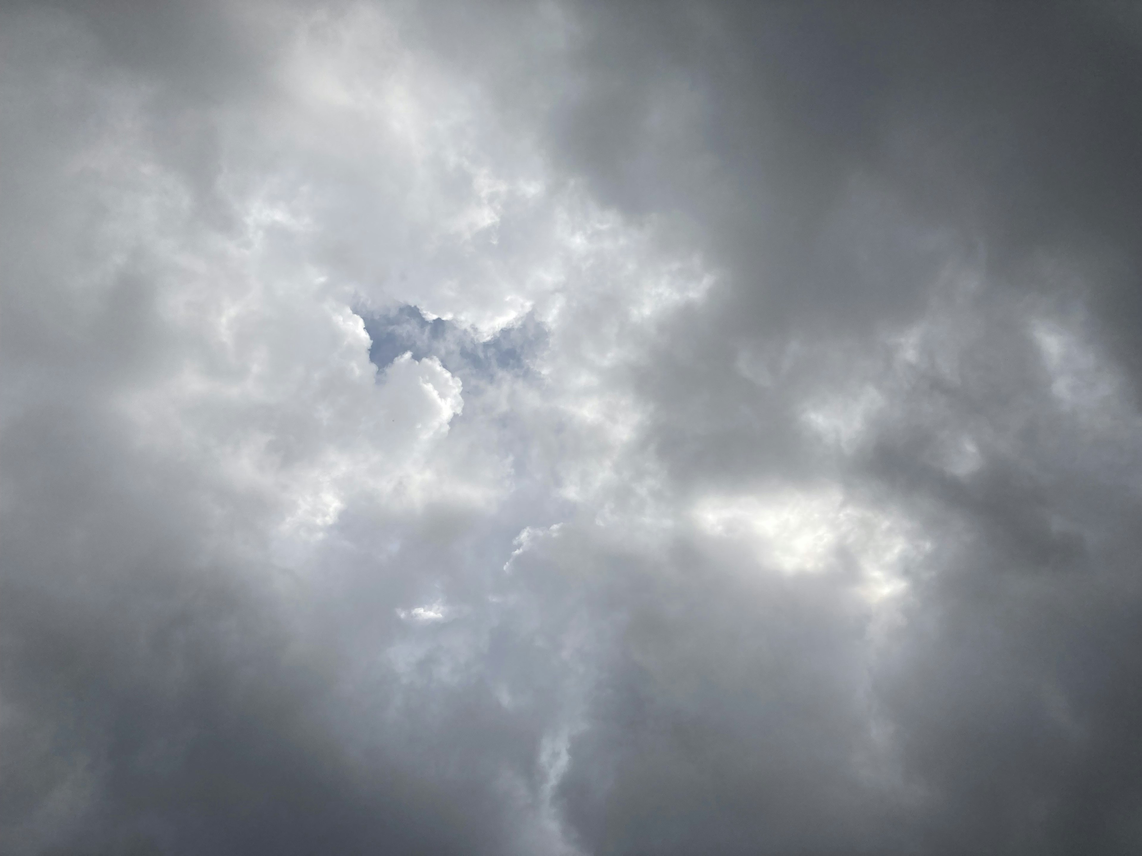 灰色の雲に覆われた空の中に青い隙間が見える