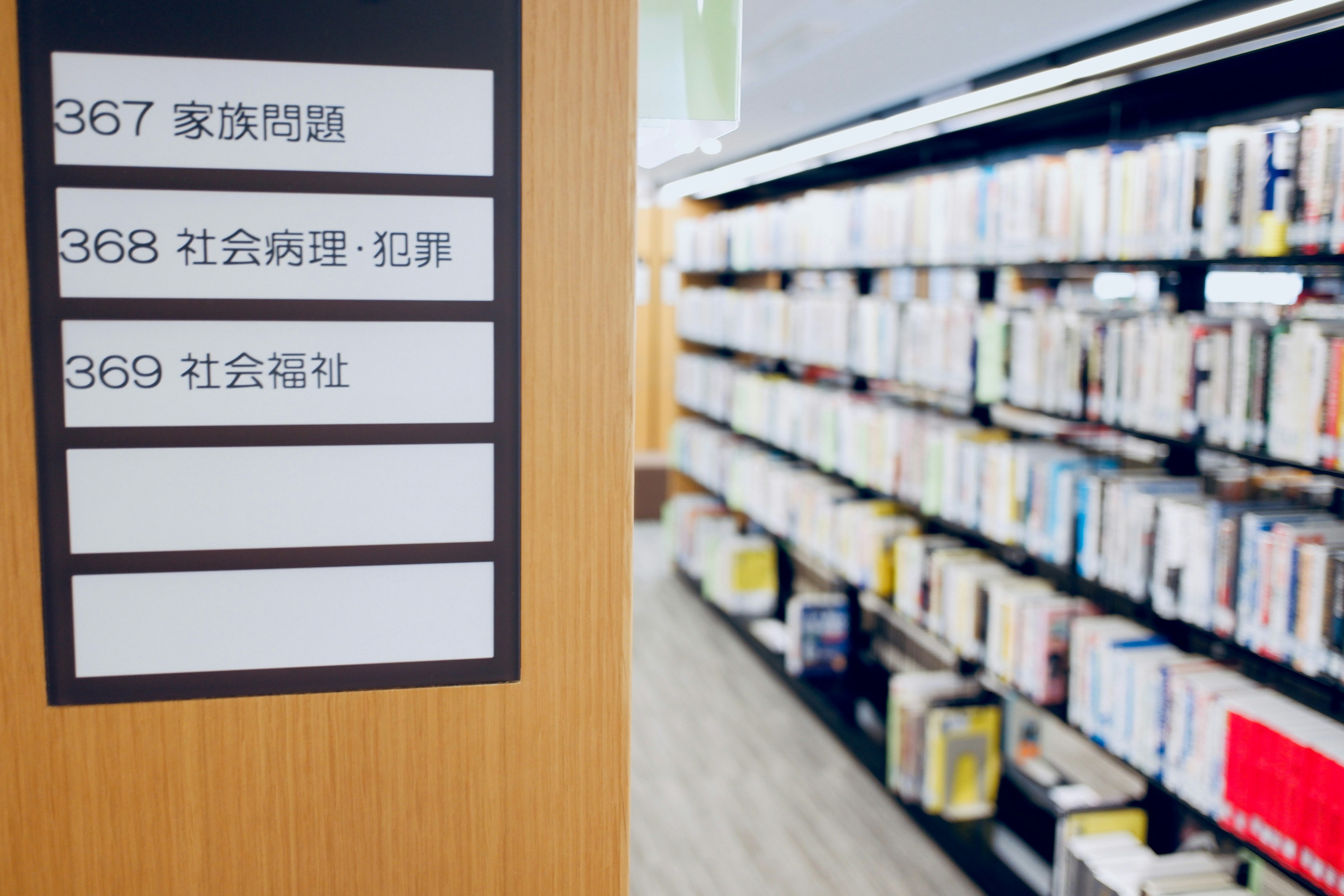 図書館の本棚の近くにある案内板と本の背表紙が並んでいる