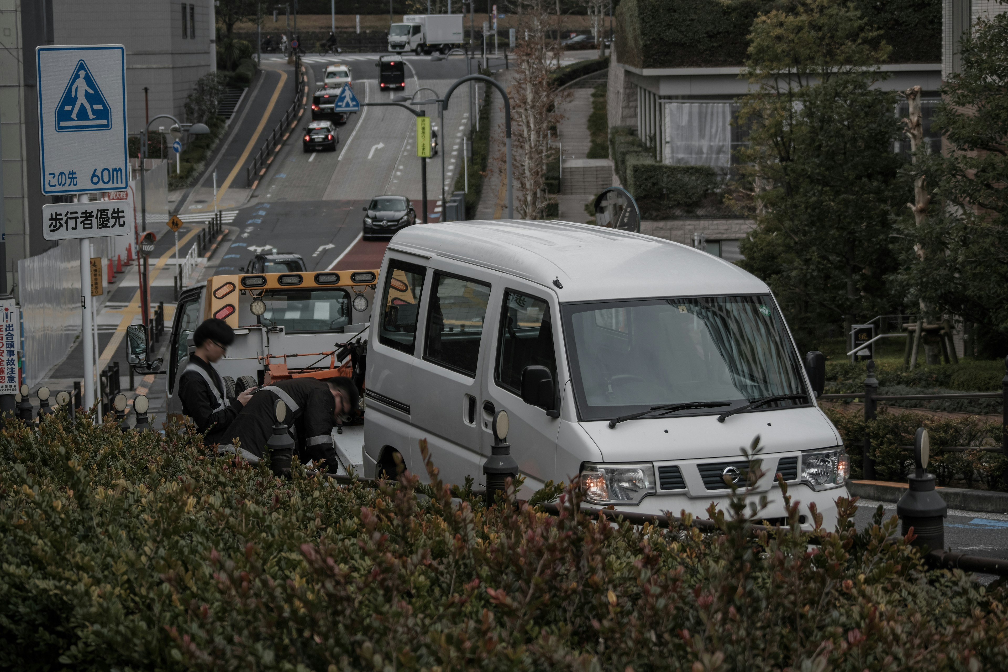 Ein weißer Van, der an einer Straße geparkt ist, umgeben von Grünpflanzen und Verkehrsschildern