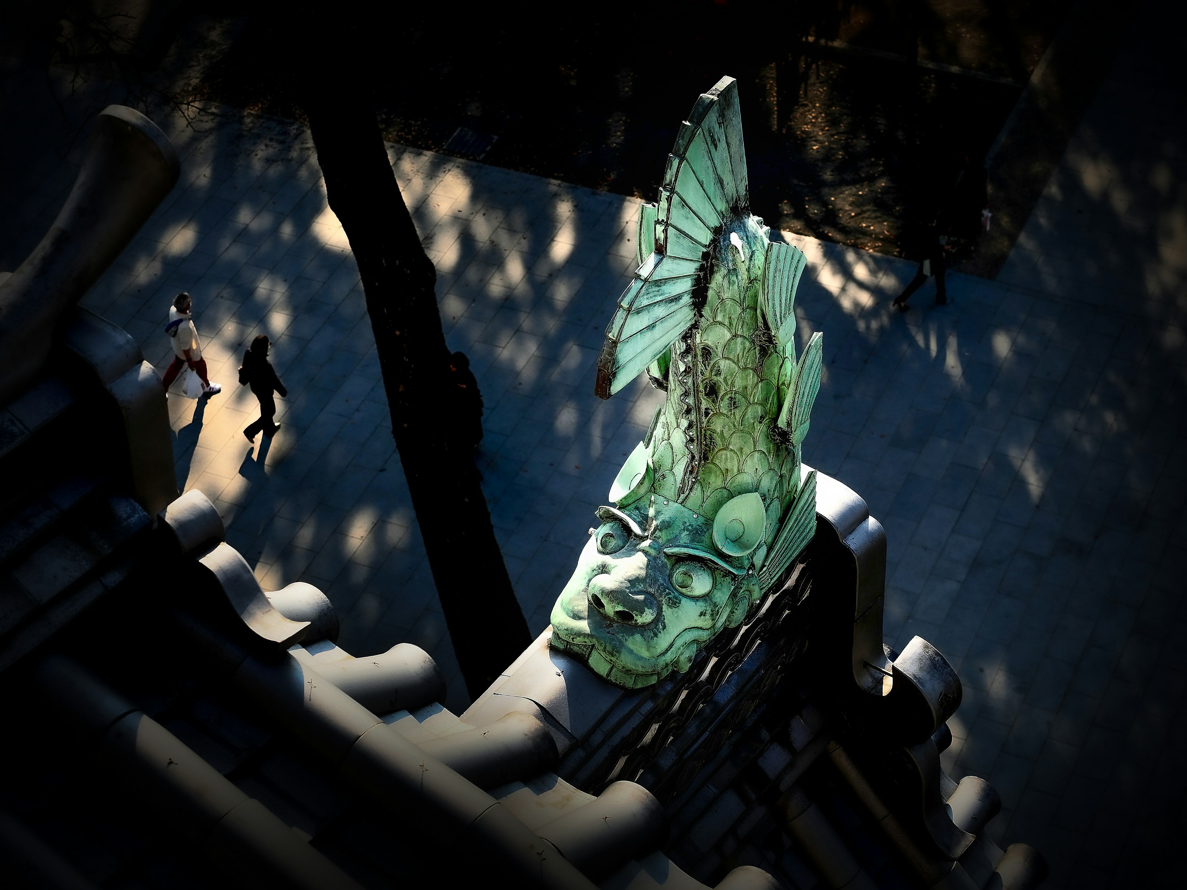 A green carved fish head sculpture placed on a rooftop