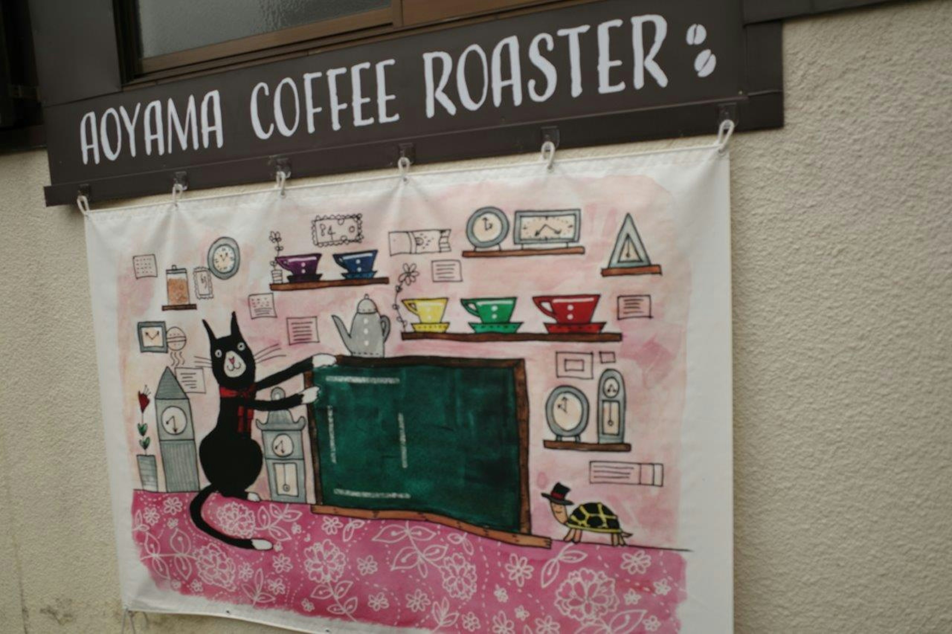 Panneau Aoyama Coffee Roaster avec des tasses à café colorées et une illustration de chat