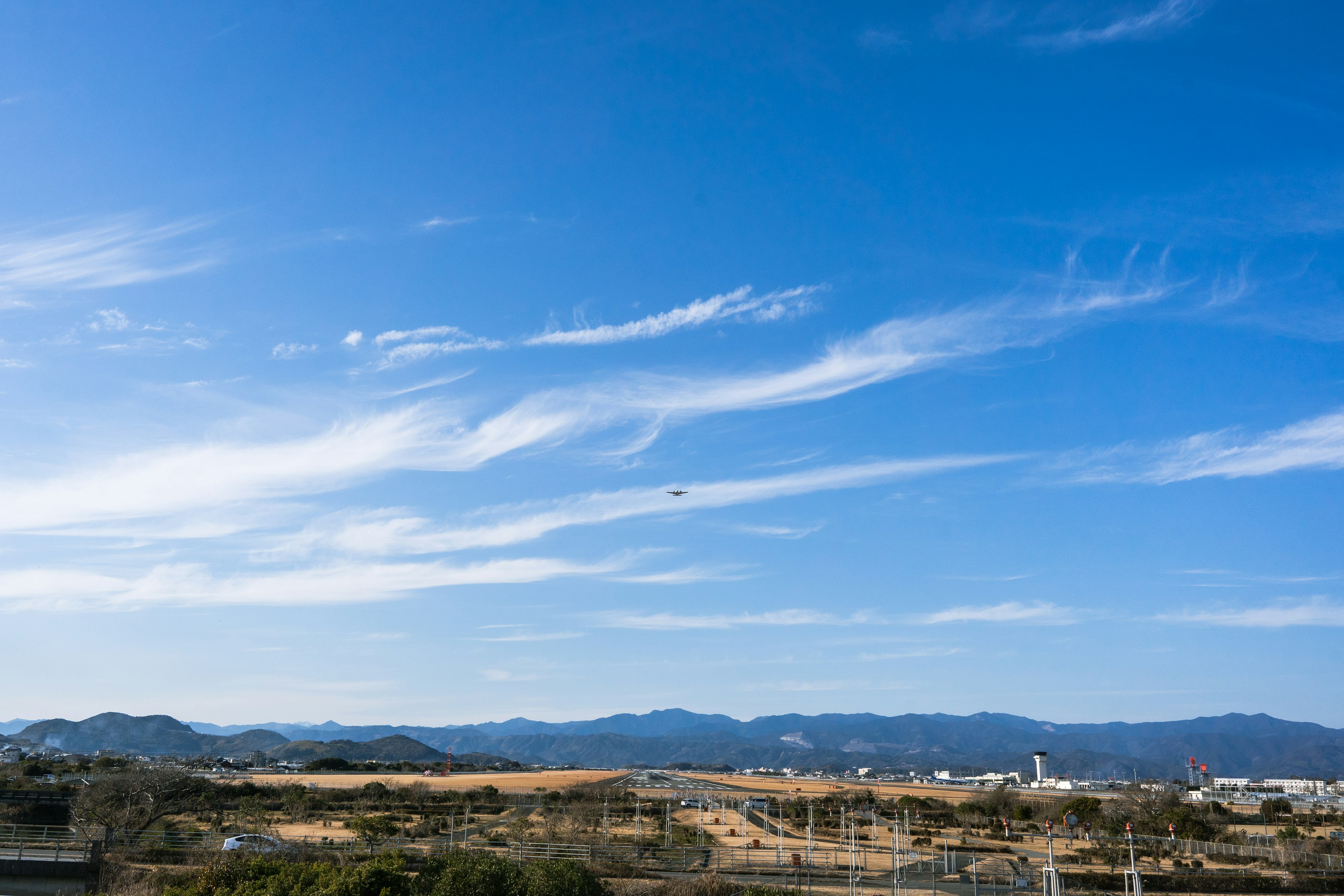 Cielo azul claro con nubes delgadas y montañas a lo lejos