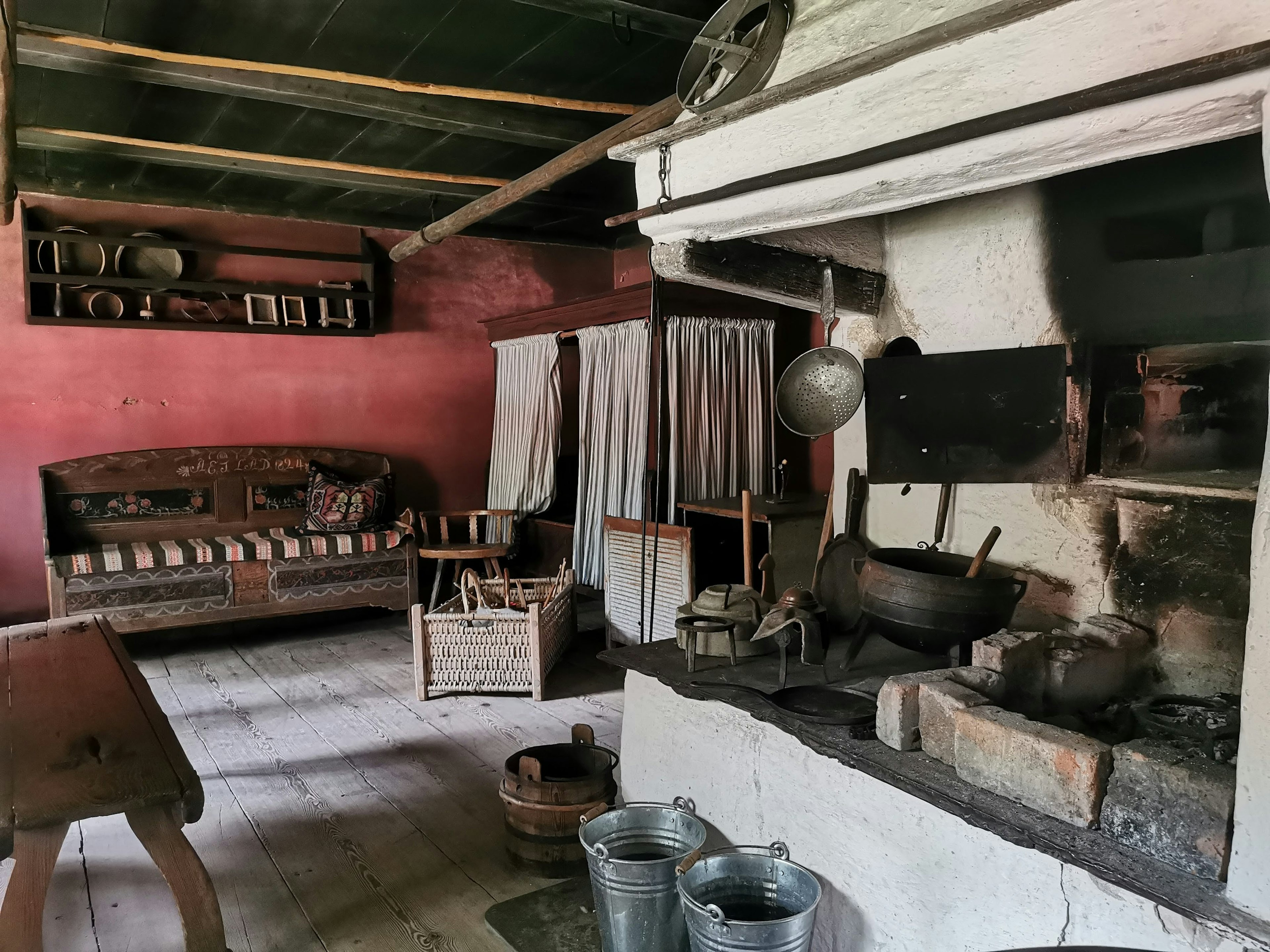 Interior de una cocina antigua con paredes rojas muebles de madera ollas y utensilios de cocina