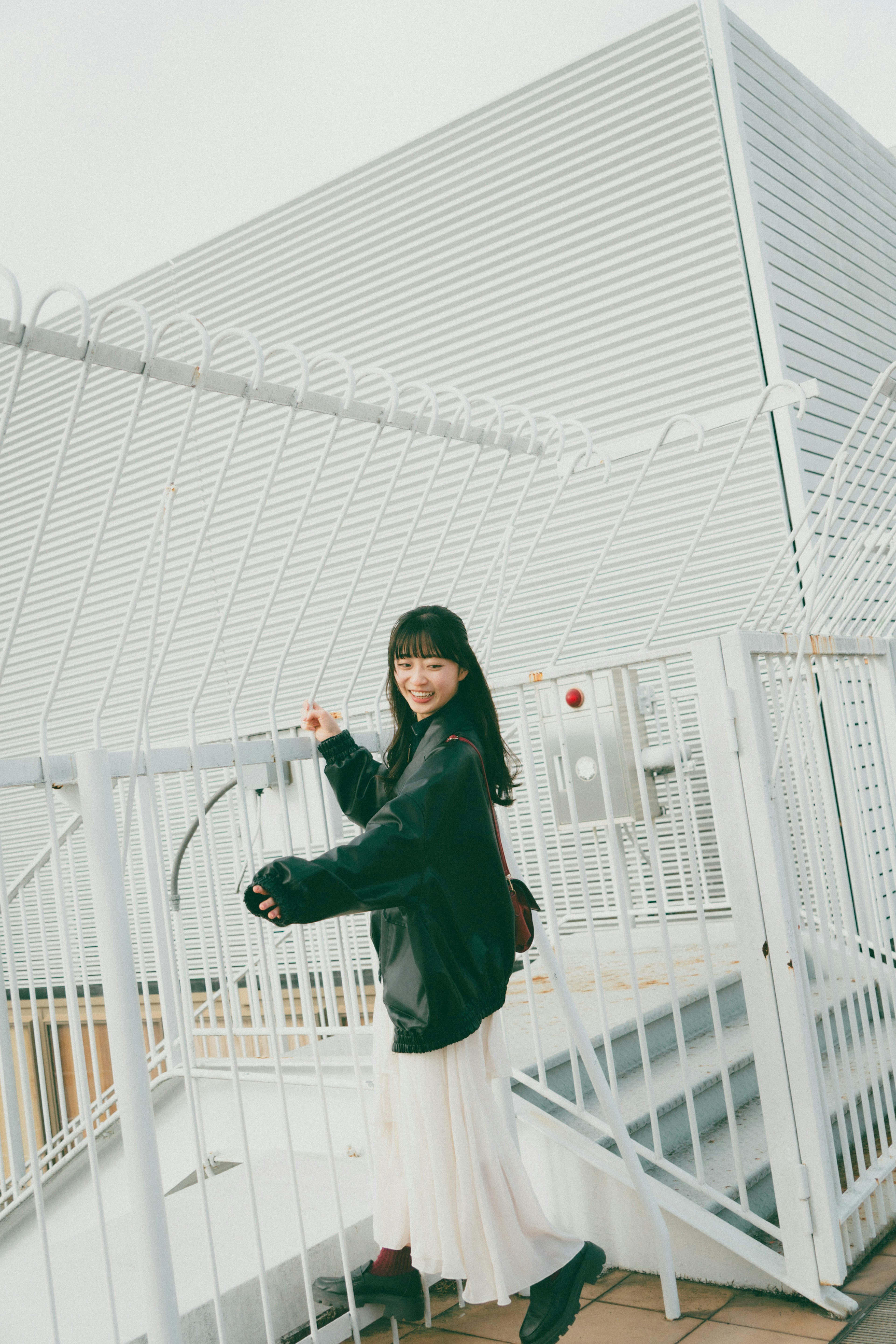 A woman in a white skirt leaning against a metal railing