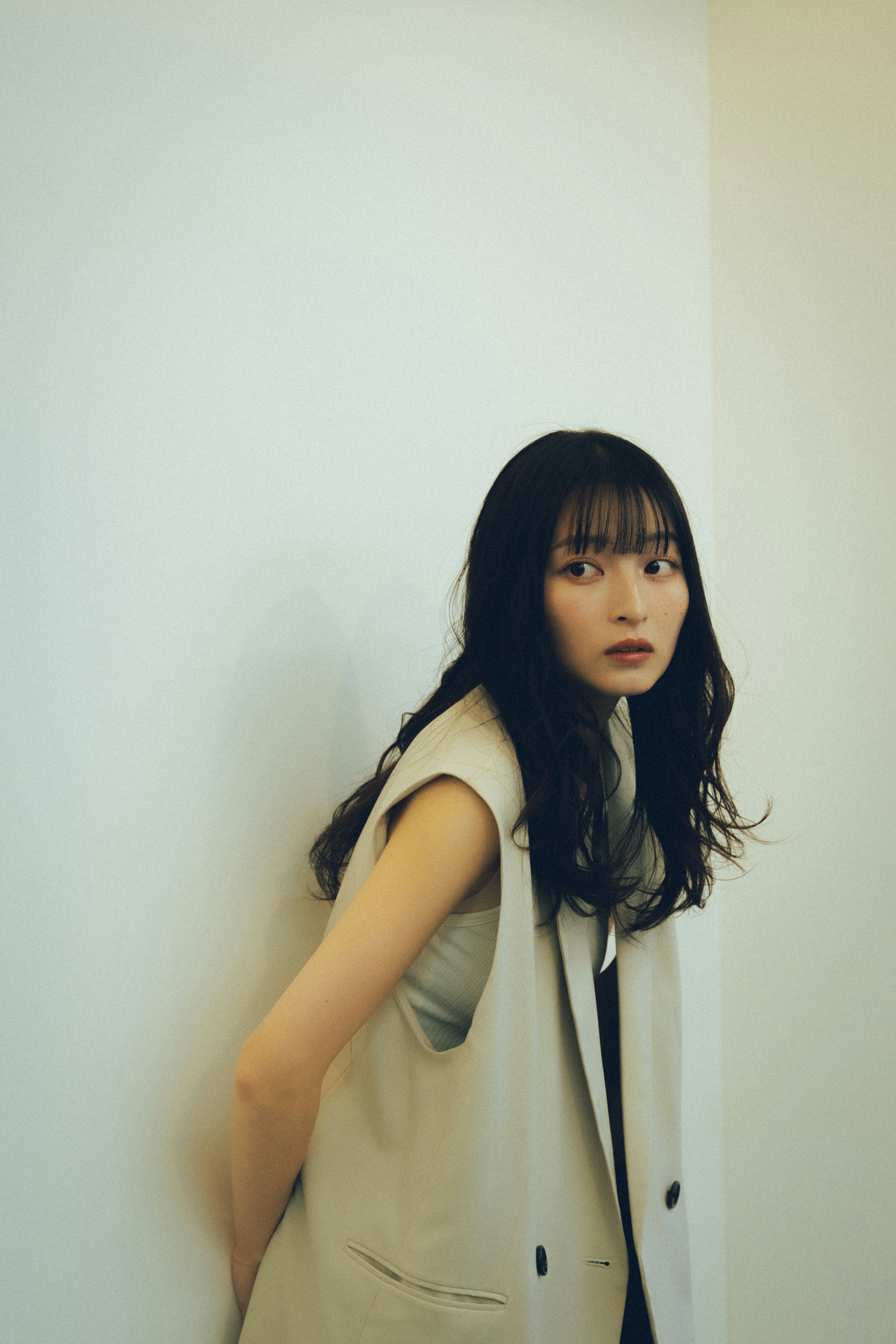 Portrait of a woman leaning against a wall with long hair and casual attire