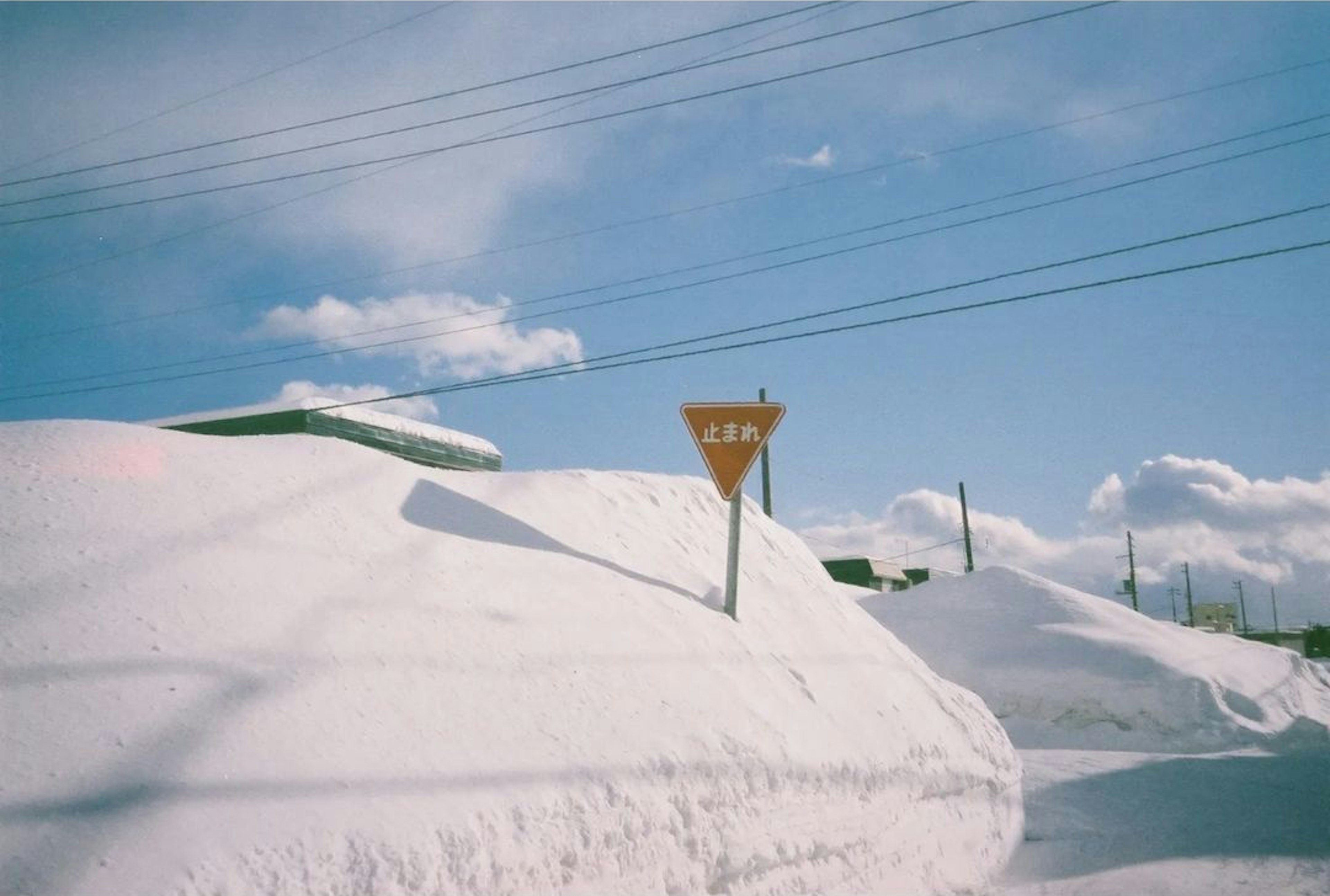 Snow-covered road sign against a blue sky