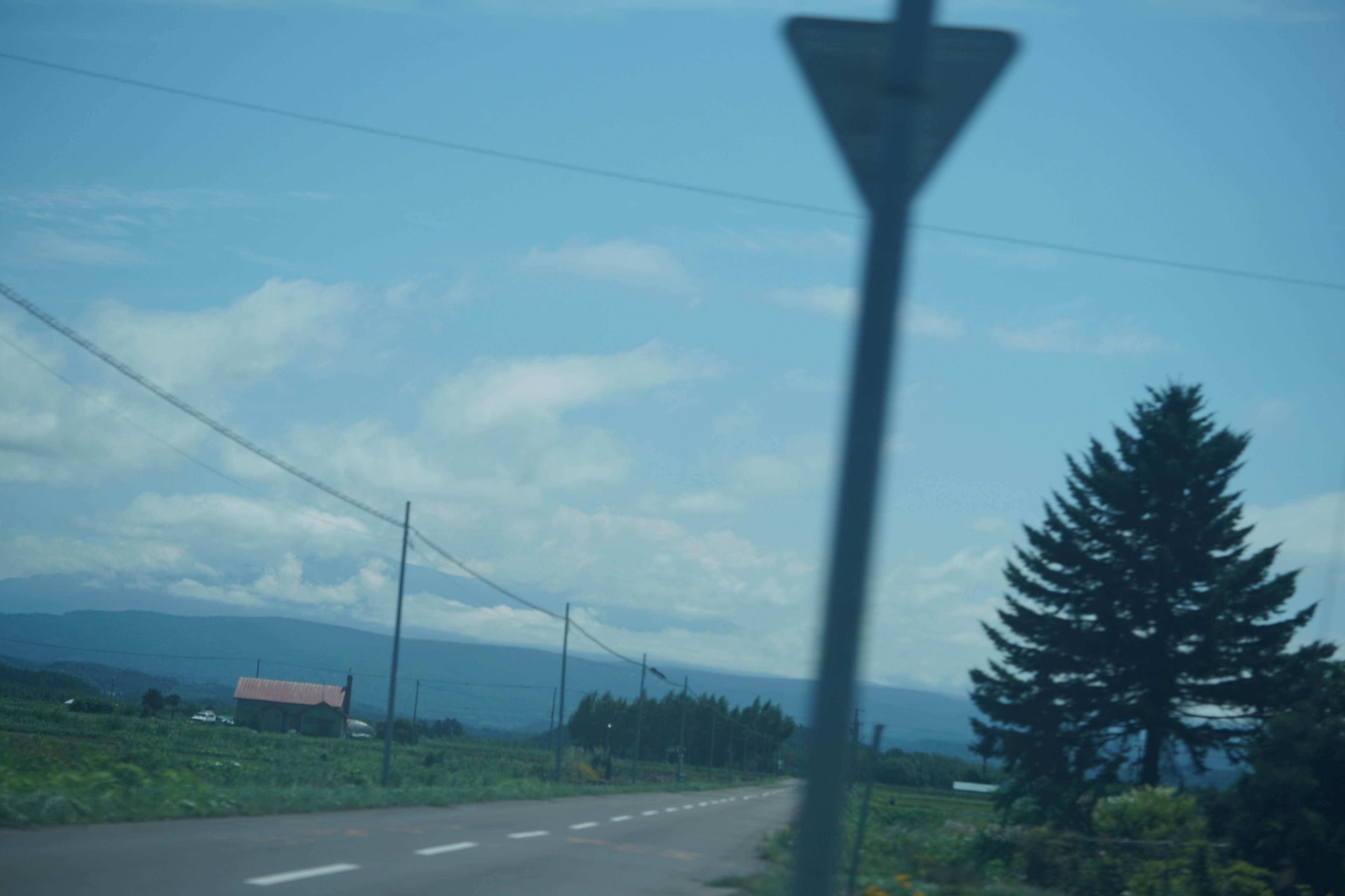 Route rurale avec un panneau sous un ciel bleu et des nuages