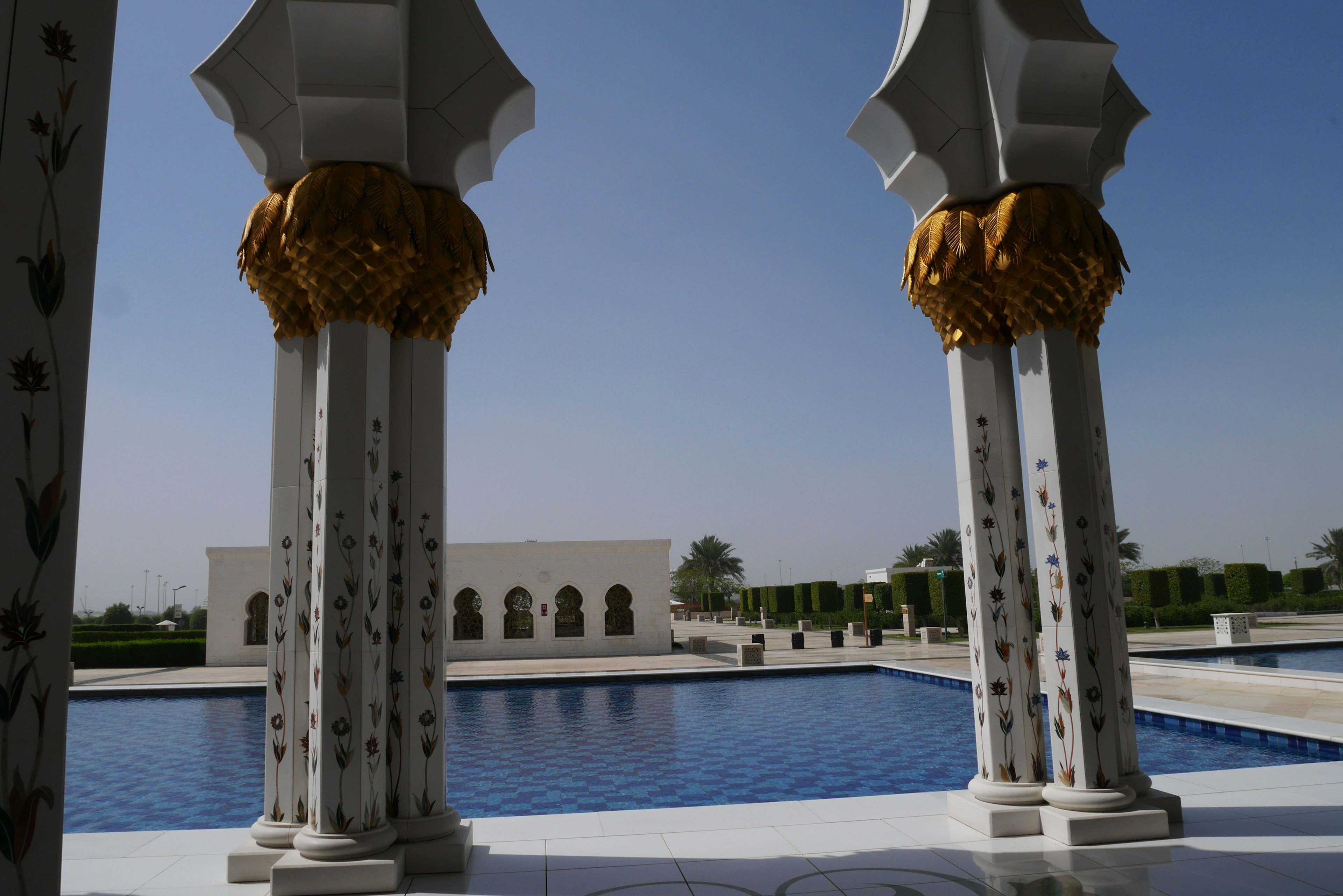 View of luxurious columns with golden accents overlooking a serene blue pool