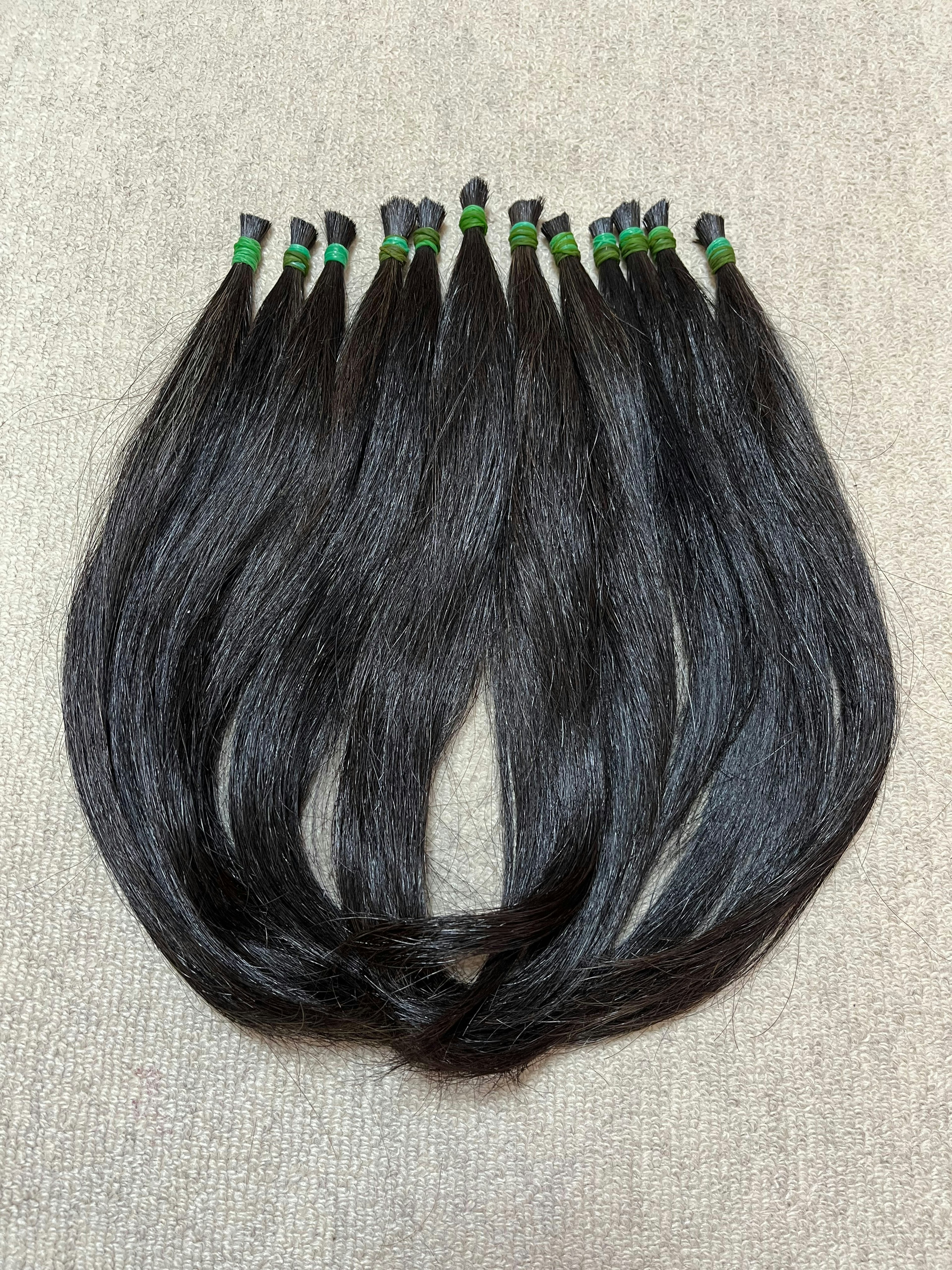 Bundles of black hair tied with green rubber bands arranged neatly