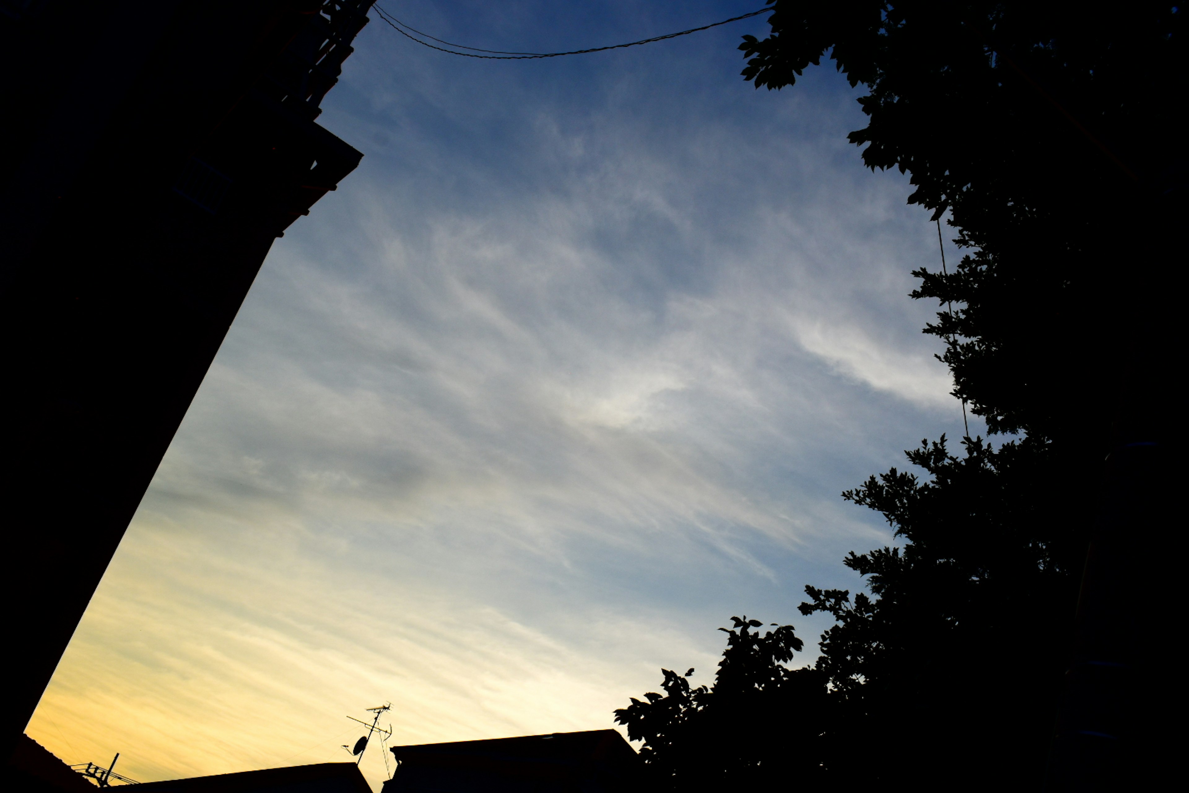 Cielo al atardecer con nubes finas y siluetas de edificios