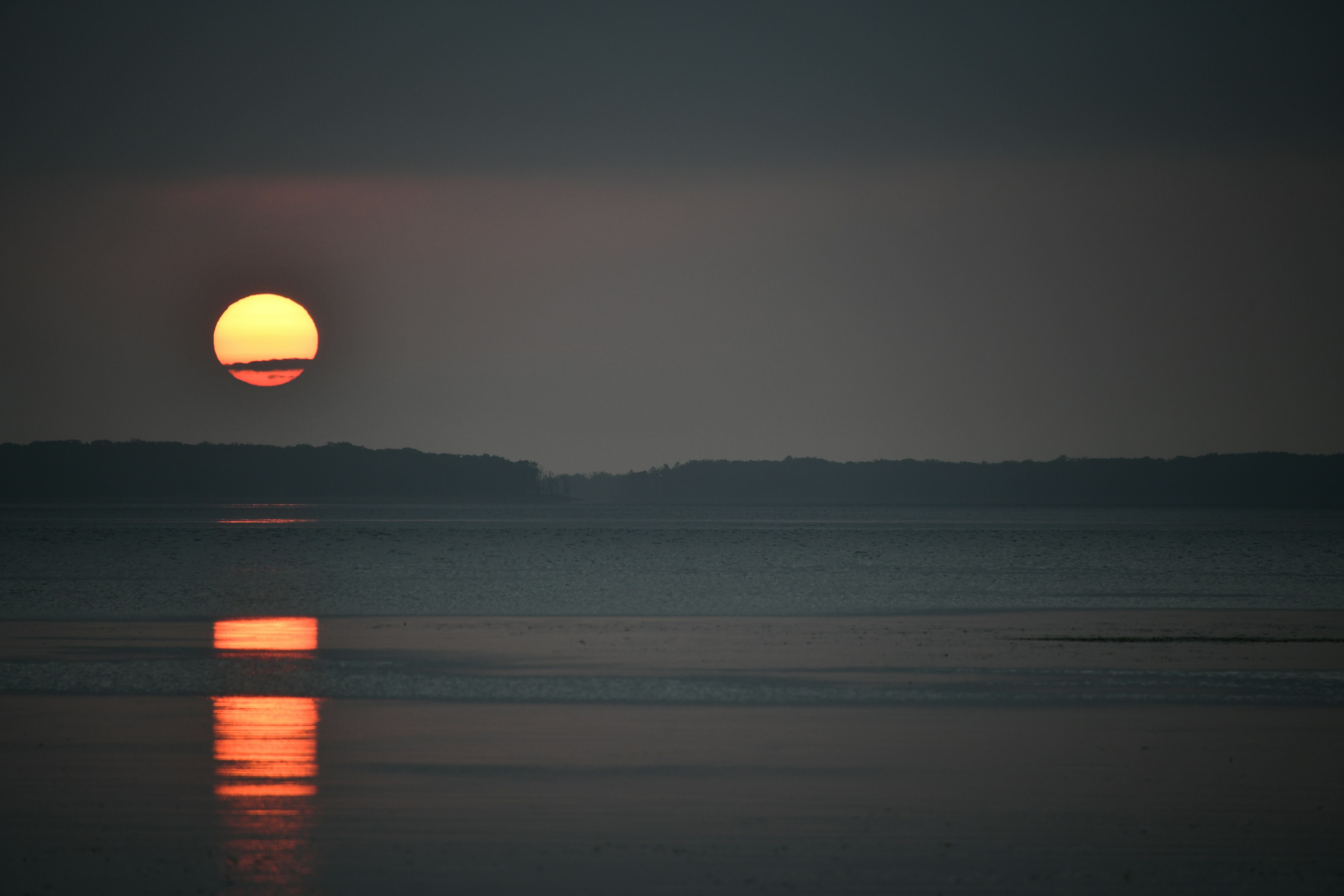 Eine ruhige Seesicht mit einem Sonnenuntergang, der sich im Wasser spiegelt