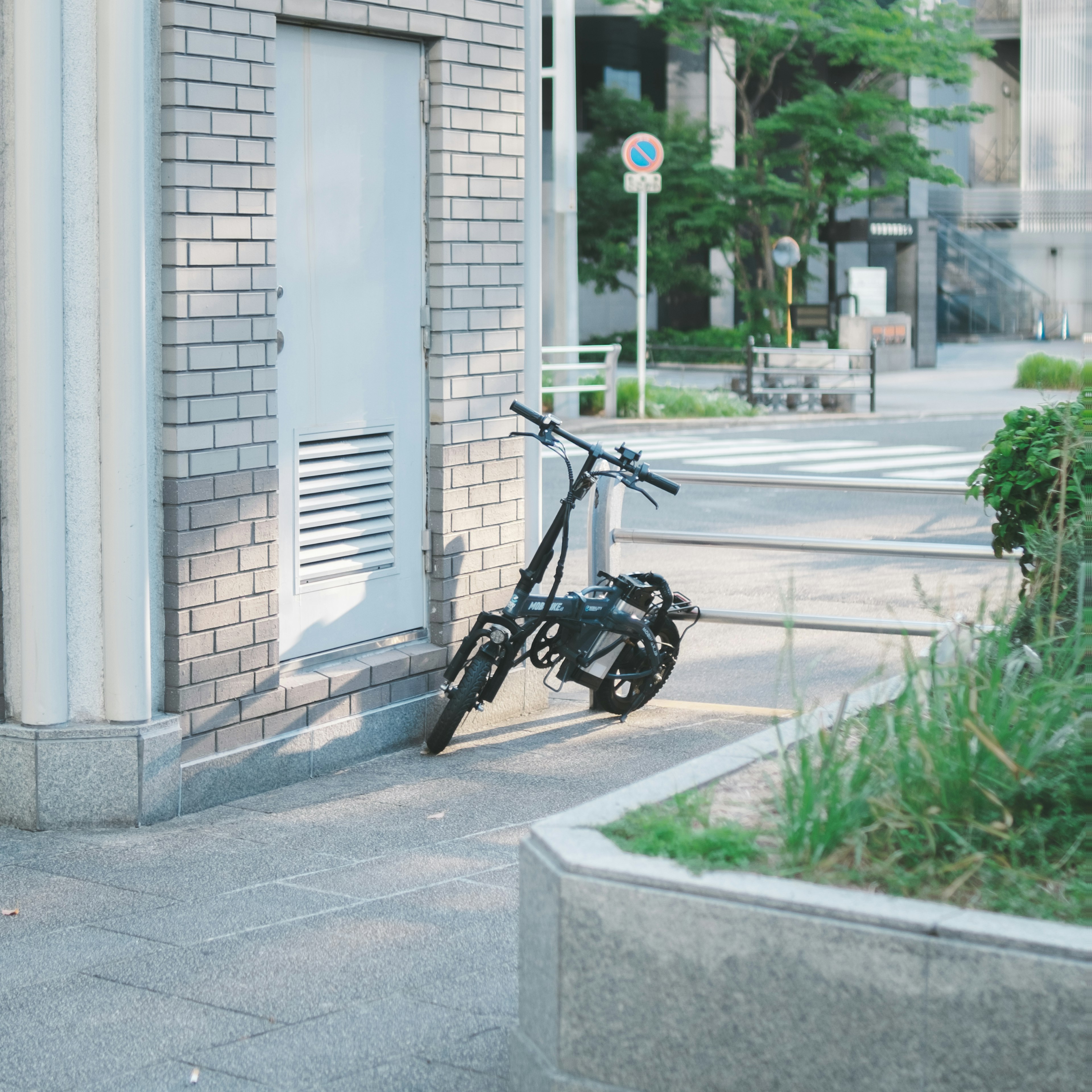 黒い折りたたみ自転車が街角に停められている風景