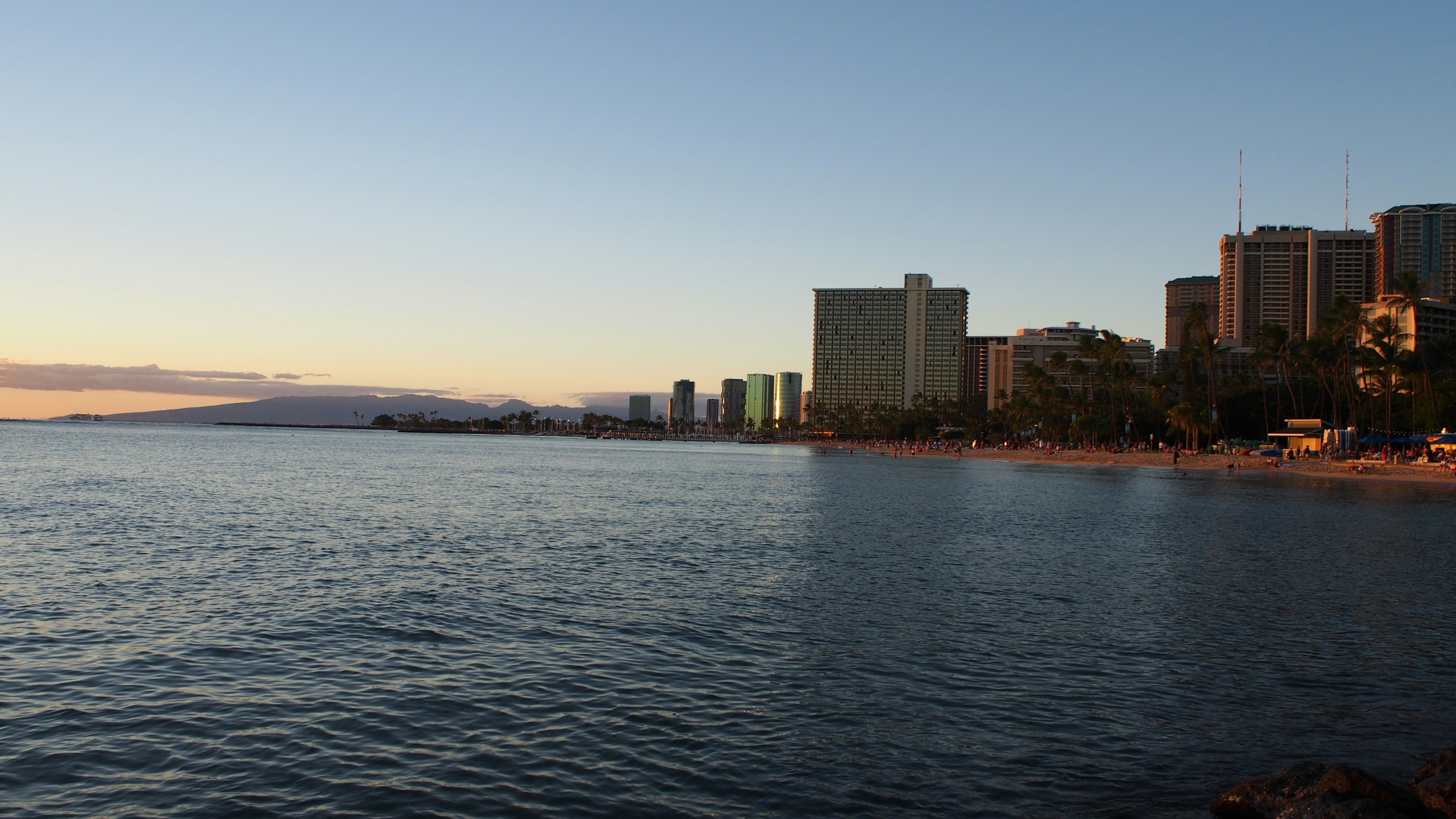 Vista del océano al atardecer con edificios altos a lo largo de la playa de Waikiki