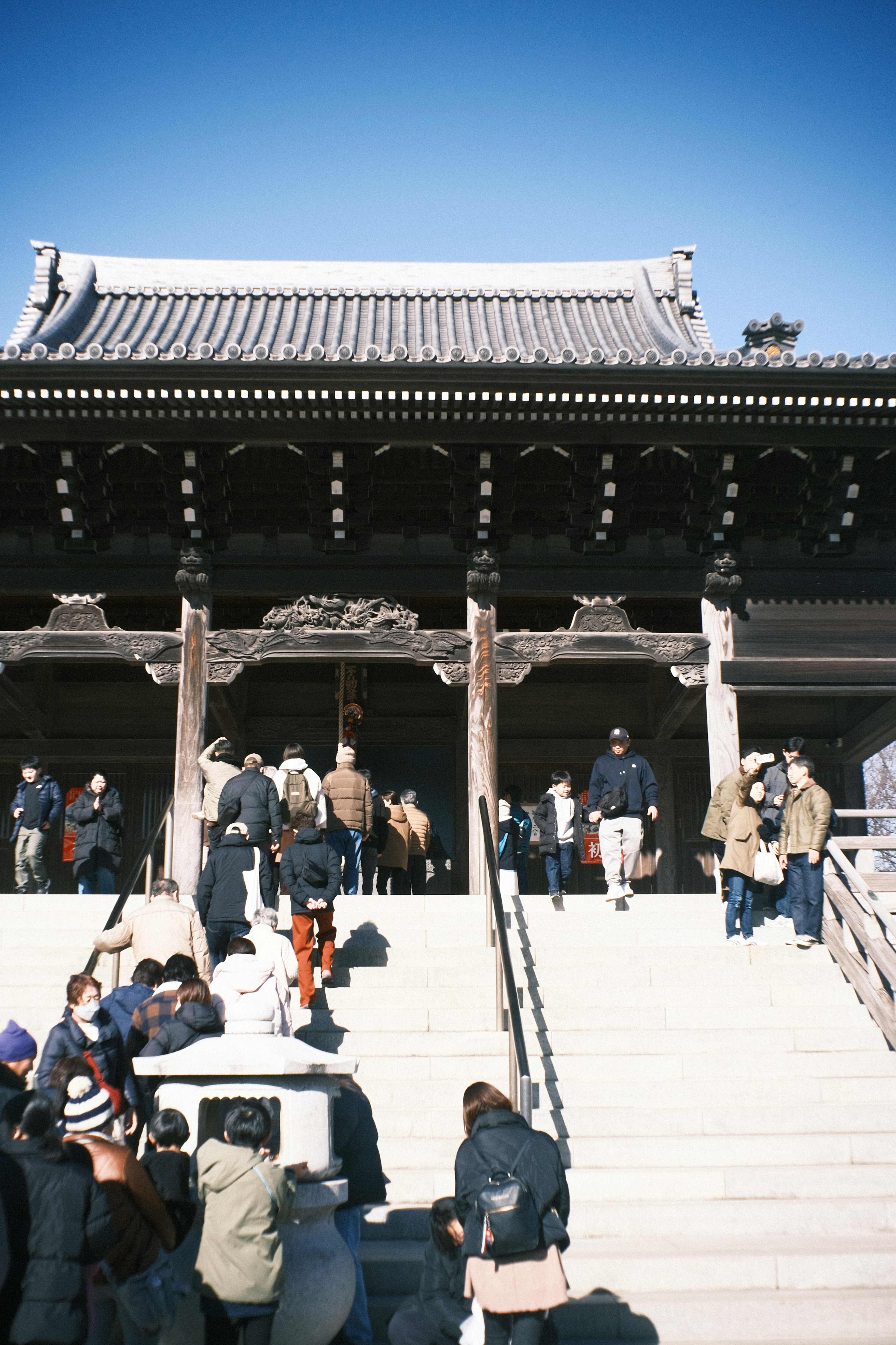 Personas subiendo escaleras en la entrada de un edificio japonés tradicional