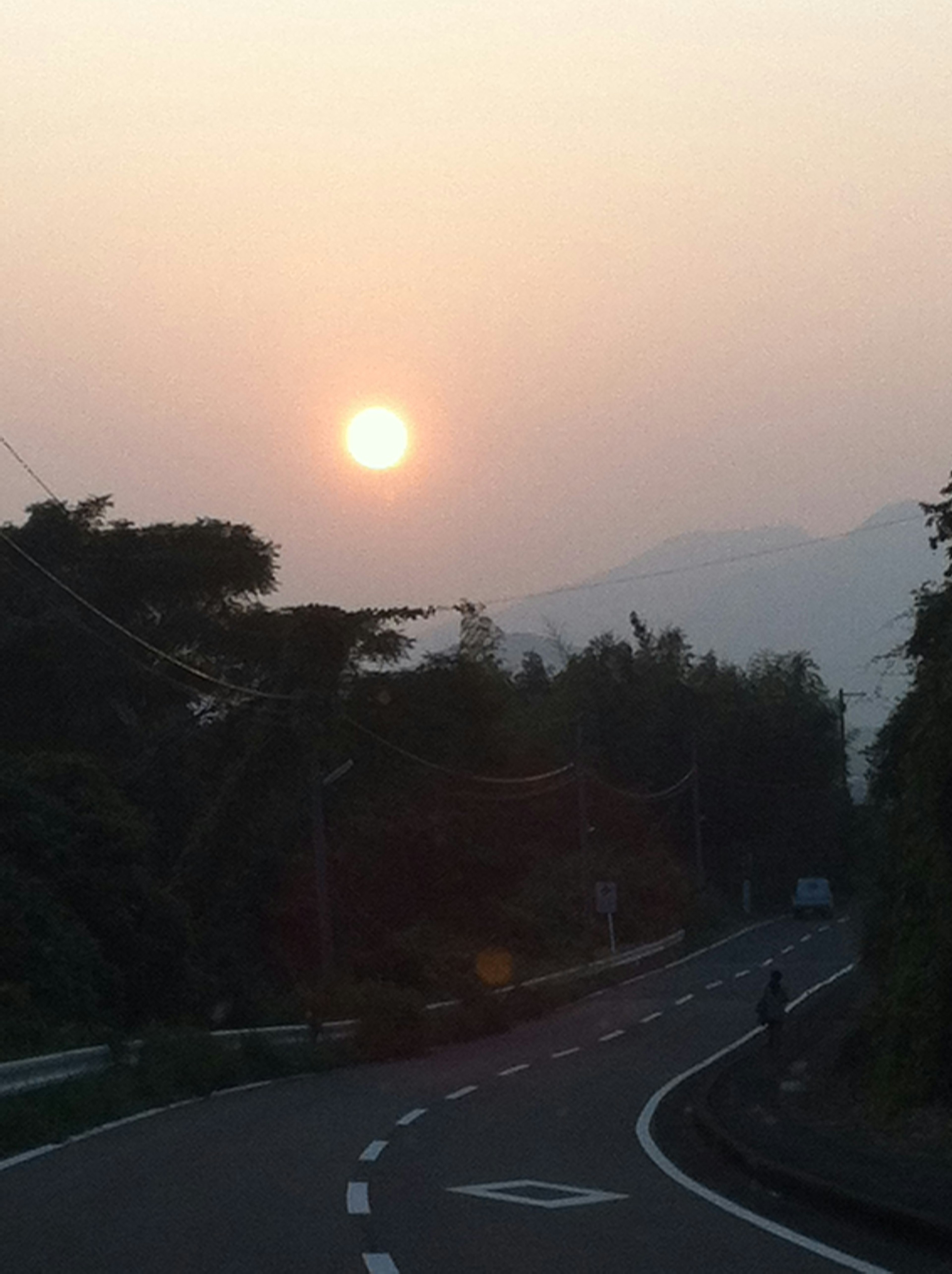 Jalan pemandangan dengan matahari terbenam dan pegunungan di latar belakang