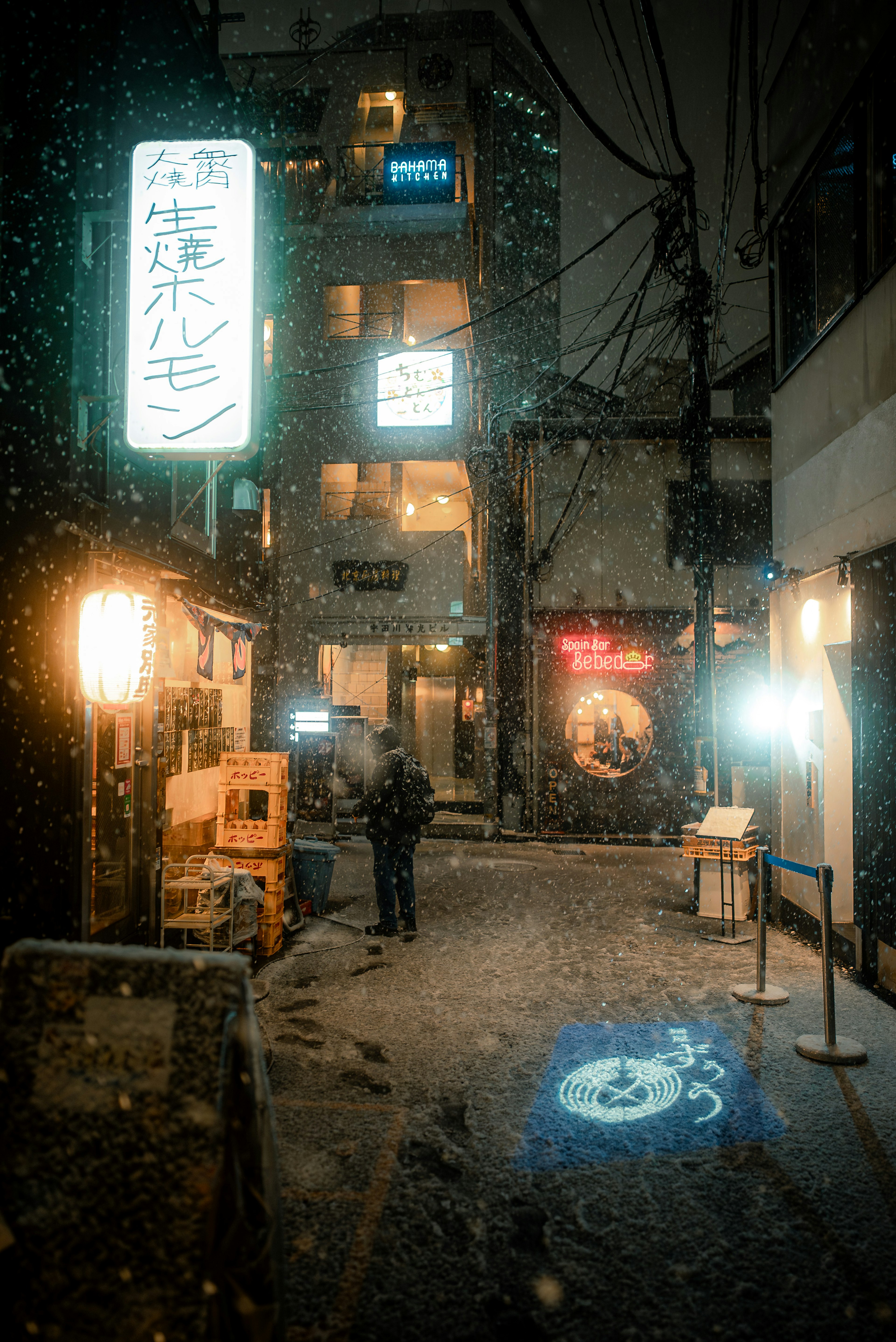 Persona in piedi in un vicolo innevato di Tokyo di notte con insegne al neon