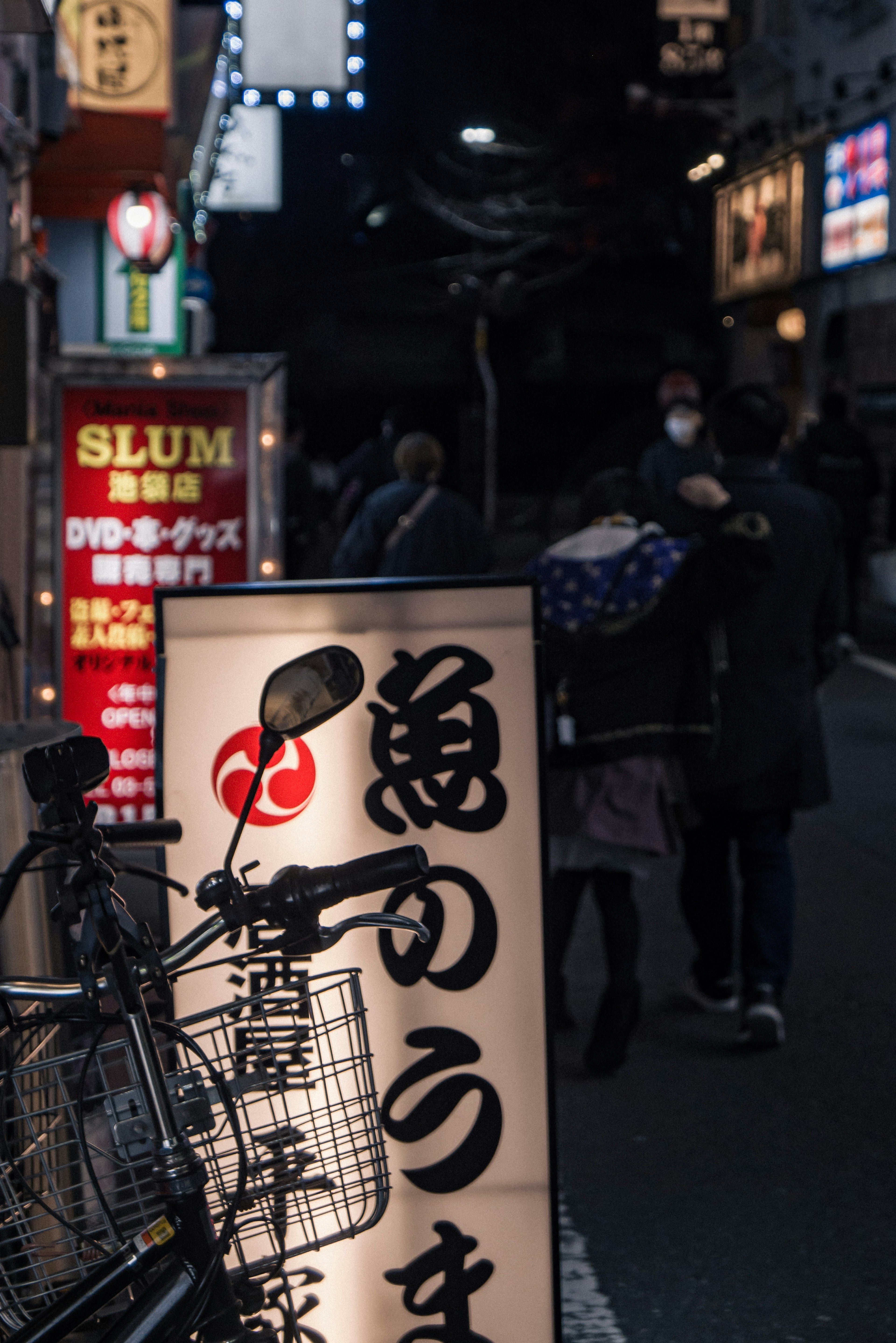 Japanisches Izakaya-Schild und Fahrrad in einer nächtlichen Straßenszene