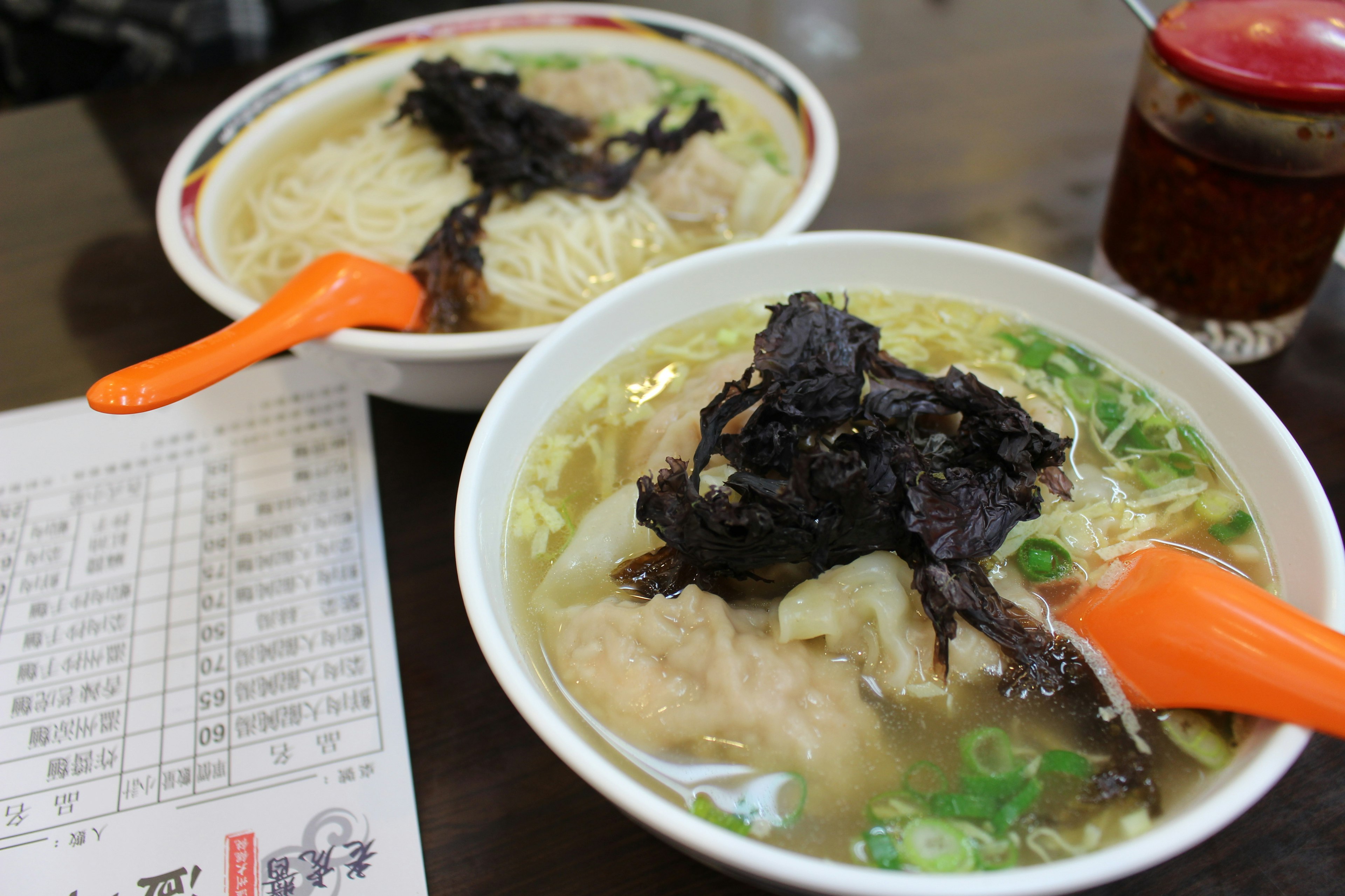 Due ciotole di ramen con alghe e condimenti su un tavolo