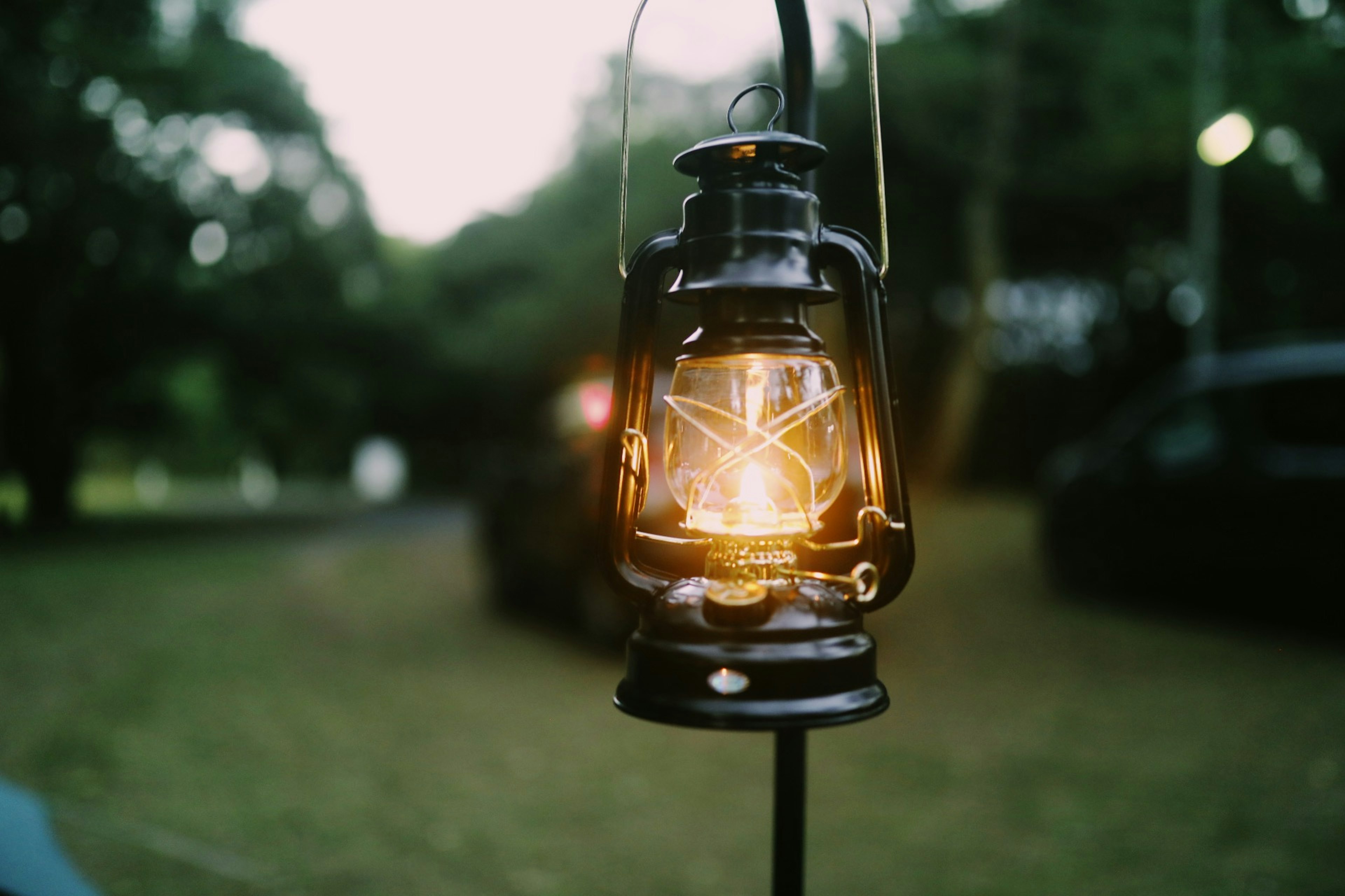 A black lantern glowing warmly in a natural setting