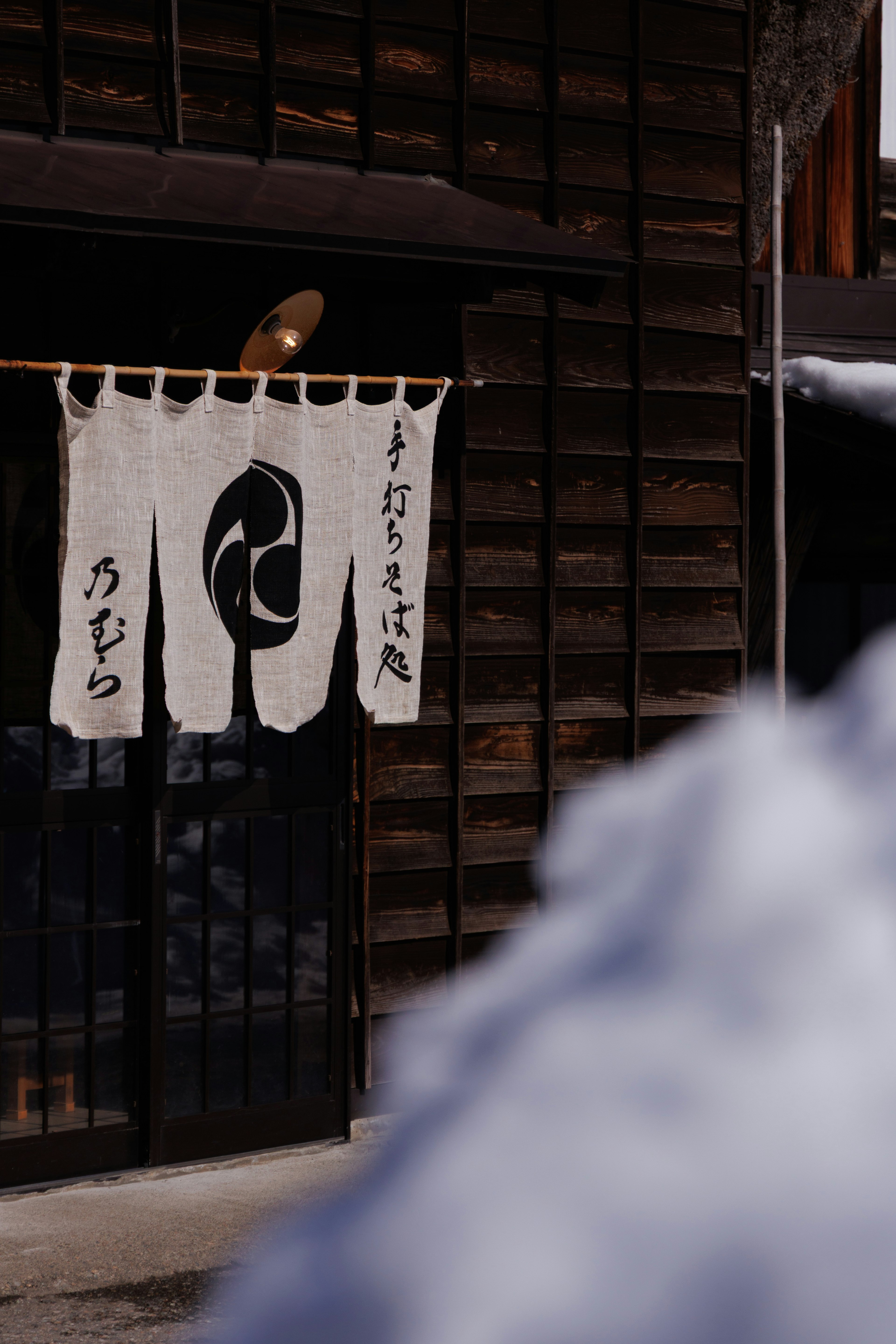 Traditional Japanese noren curtain hanging at the entrance of a wooden building