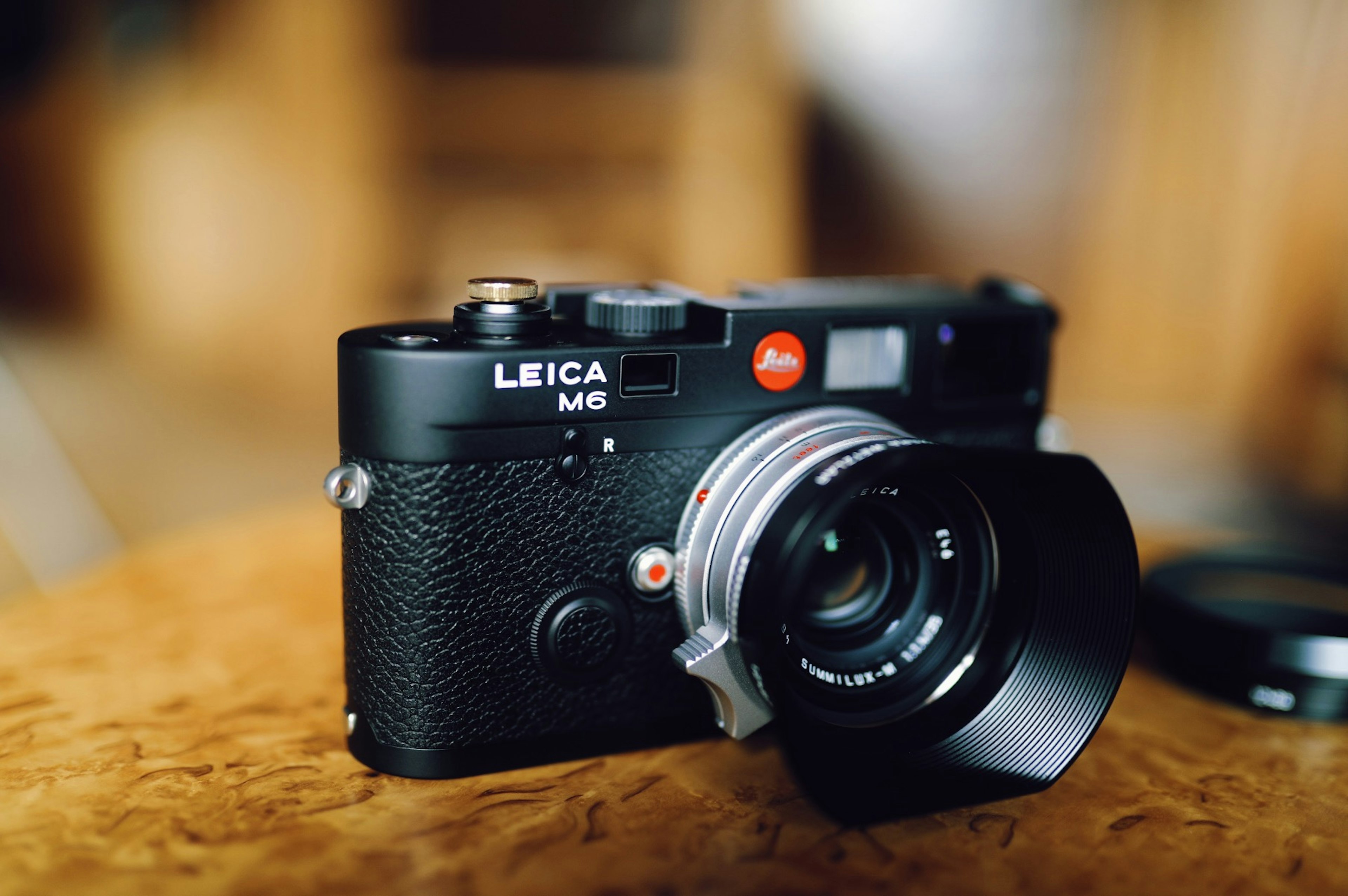 Black LEICA M6 camera placed on a wooden table