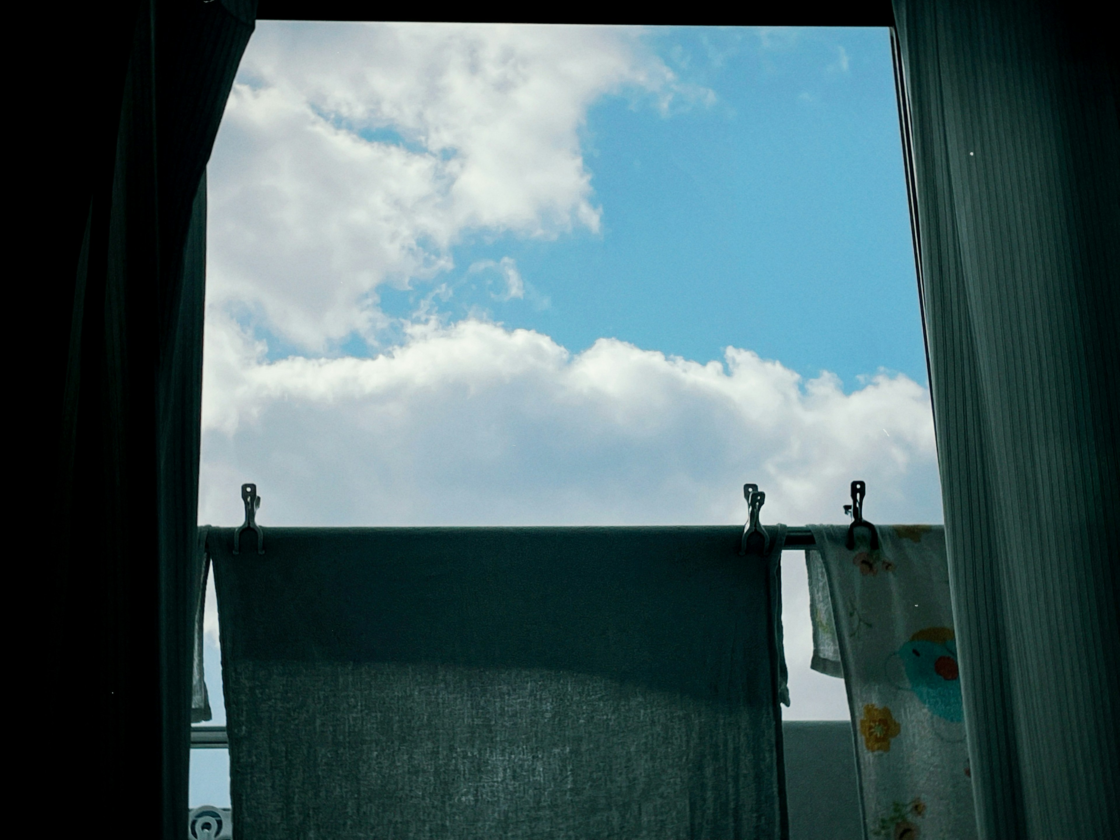 Vista de ropa colgada contra un cielo azul con nubes