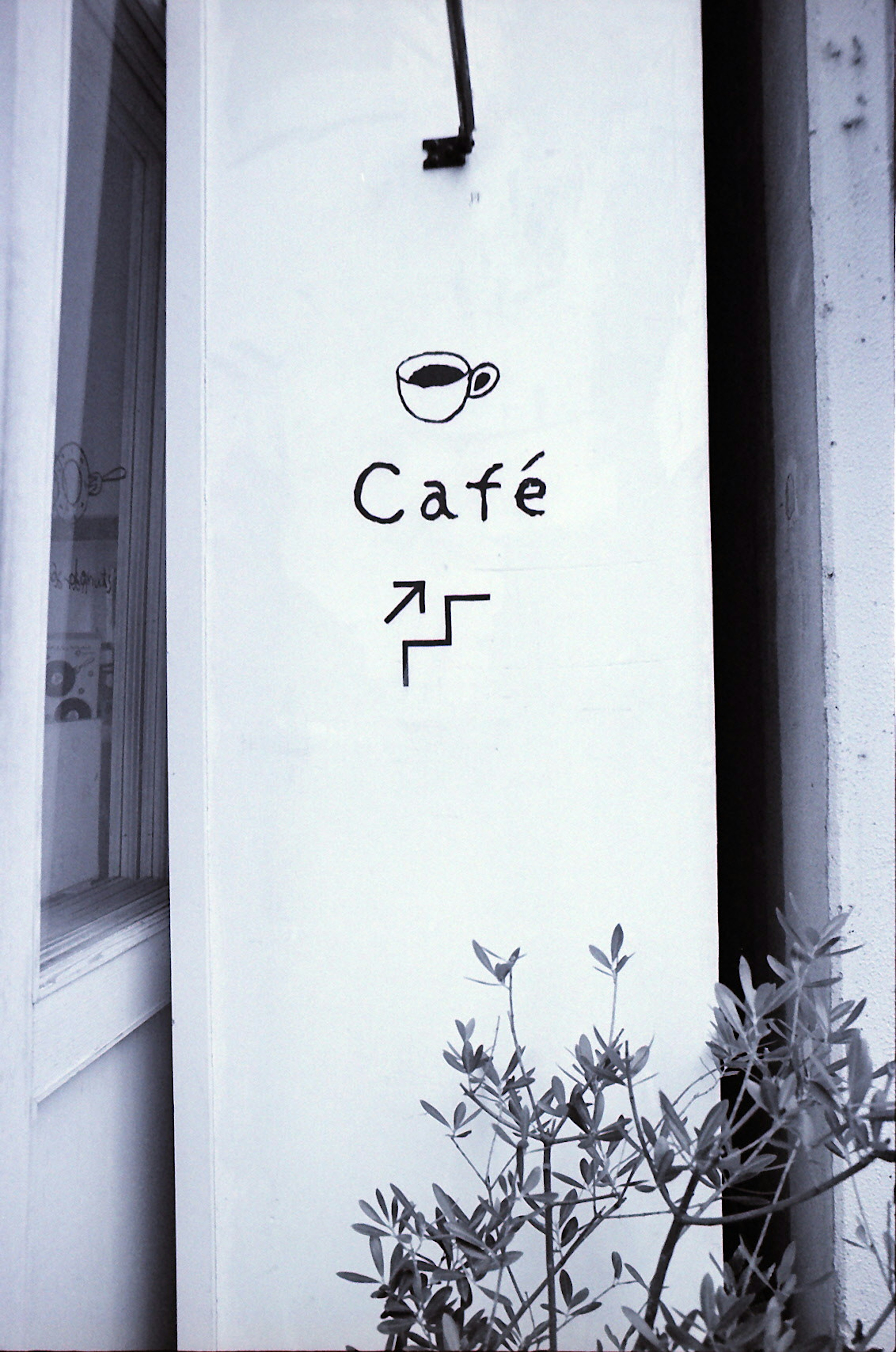 Mur blanc avec un panneau de café représentant une tasse de café et une flèche