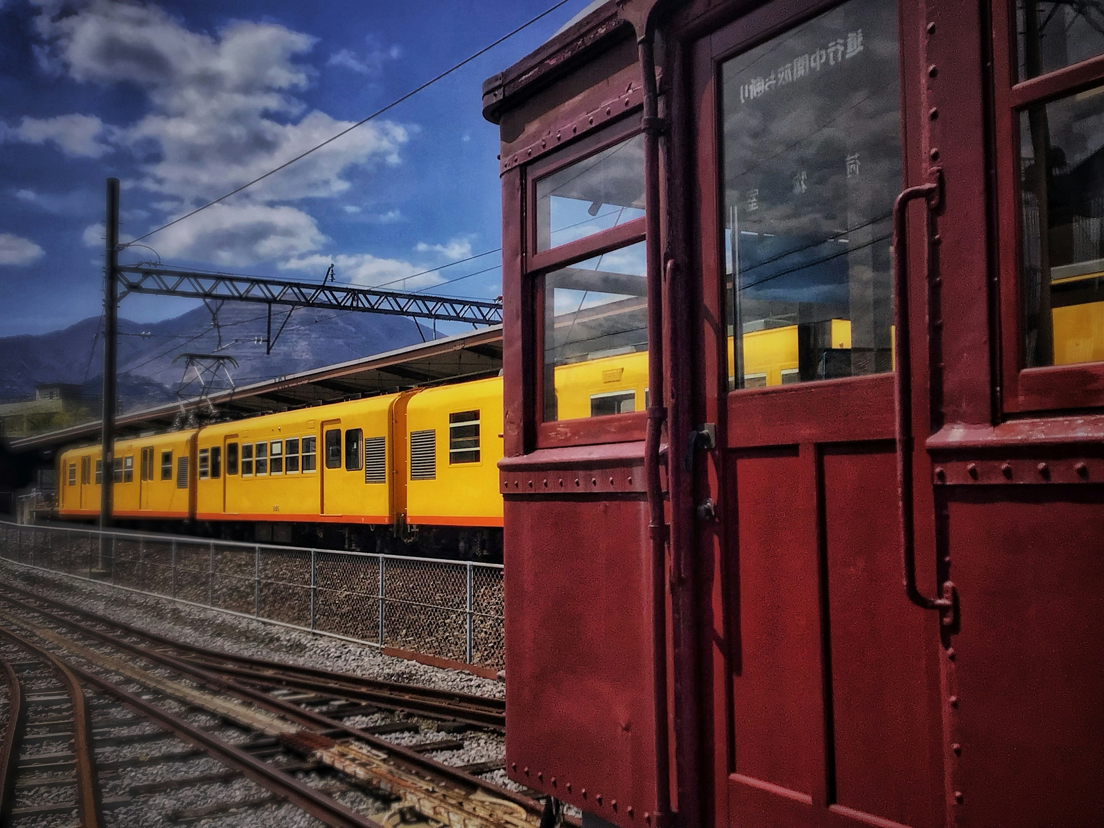 Vagón rojo al lado de un tren amarillo en la estación