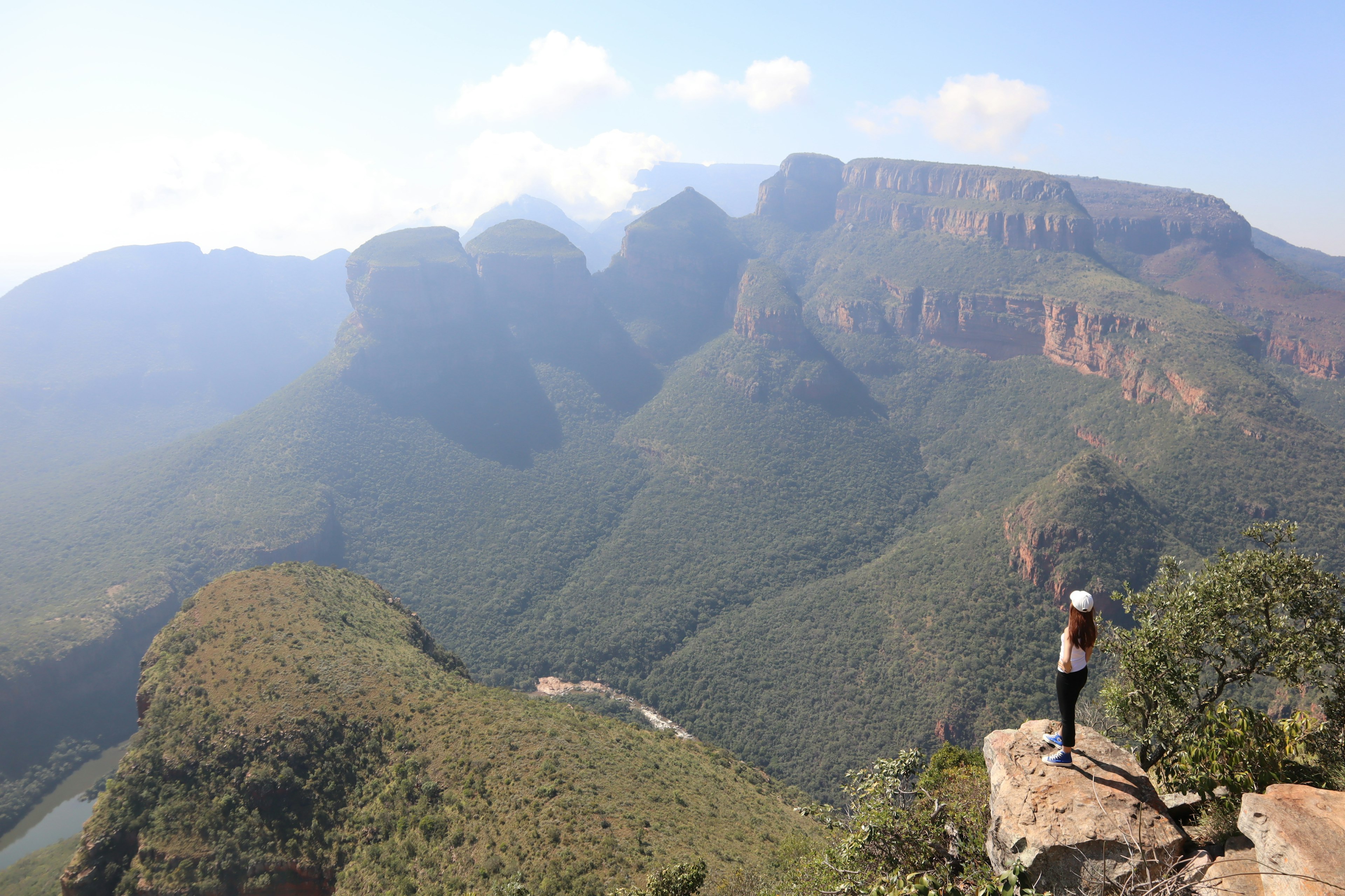 Hiker standing on a cliff with majestic mountains in the background