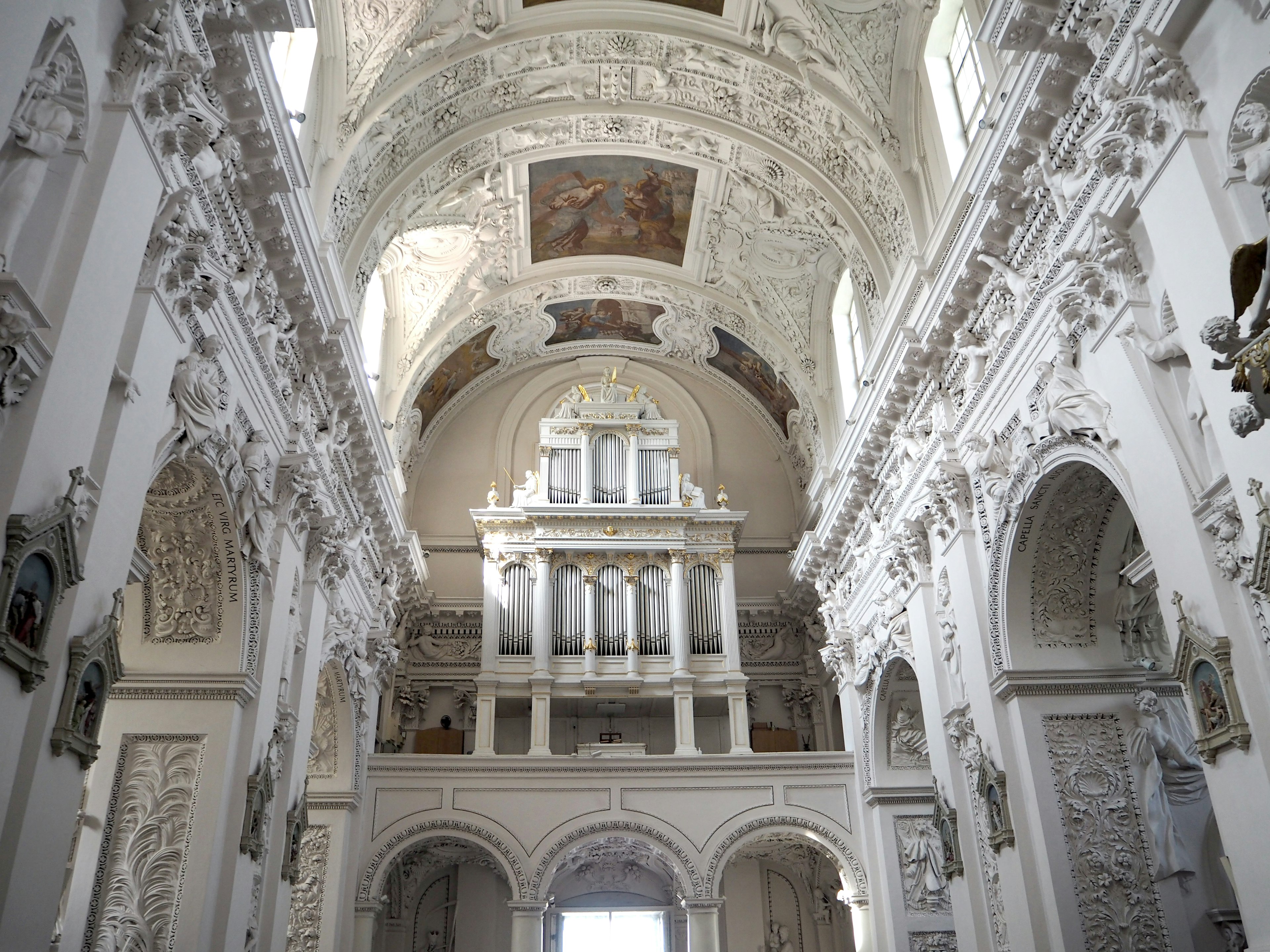 Interior of a church with white marble decorations featuring a grand ceiling and beautiful sculptures