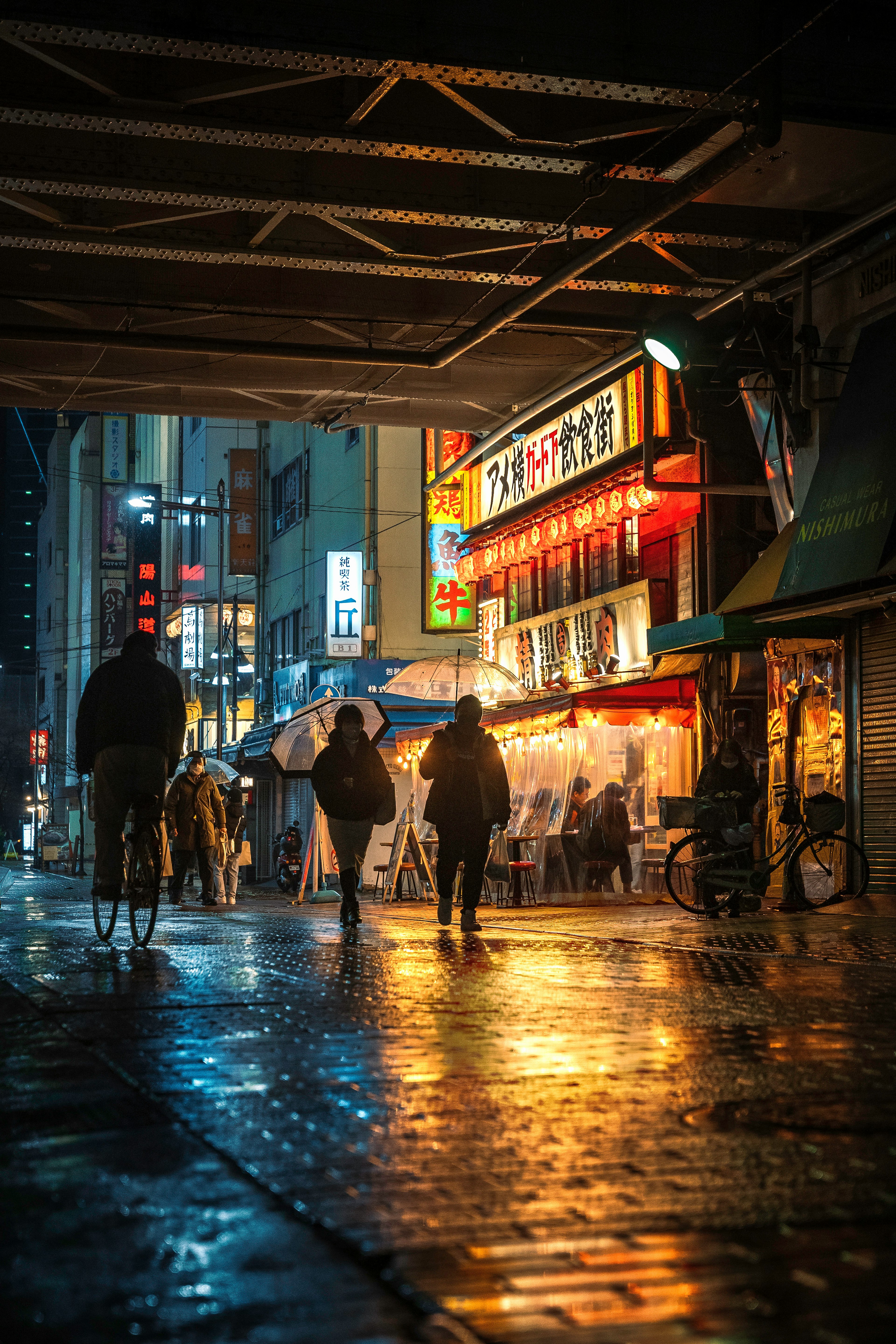 雨に濡れた街の夜景で人々が歩いている様子