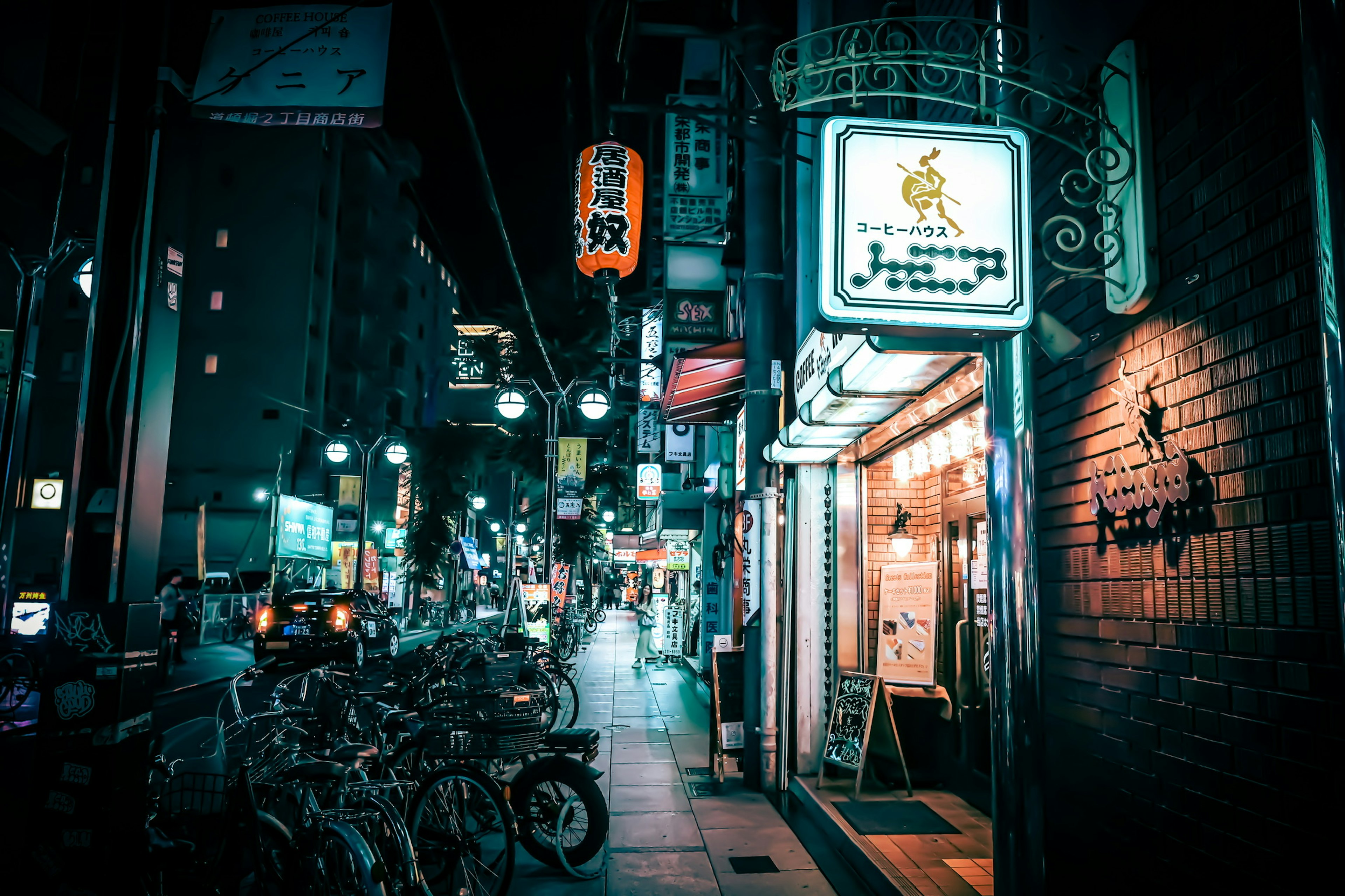 夜の街並みに並ぶ自転車と明るい看板のある通り