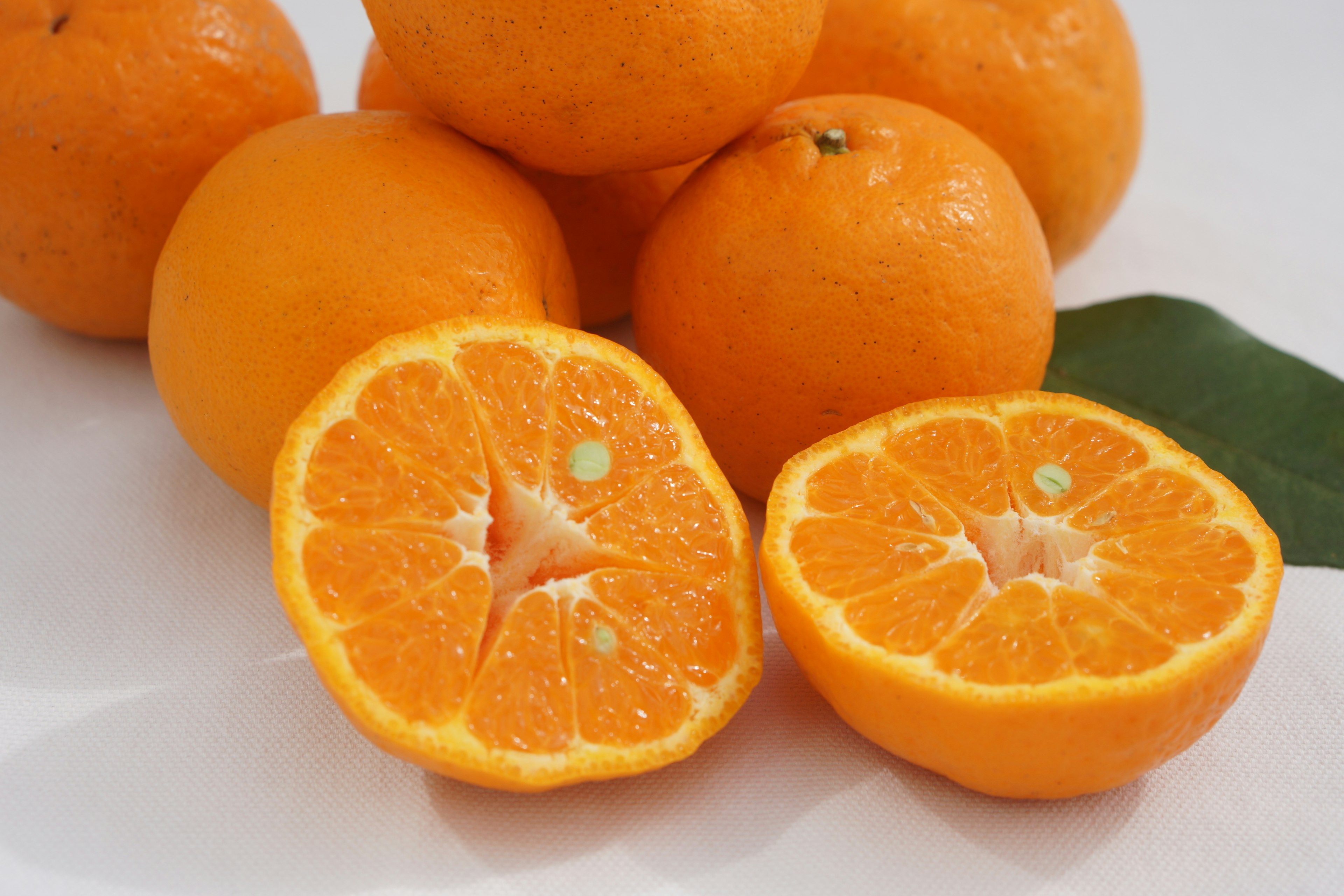 A pile of fresh oranges with one orange cut in half