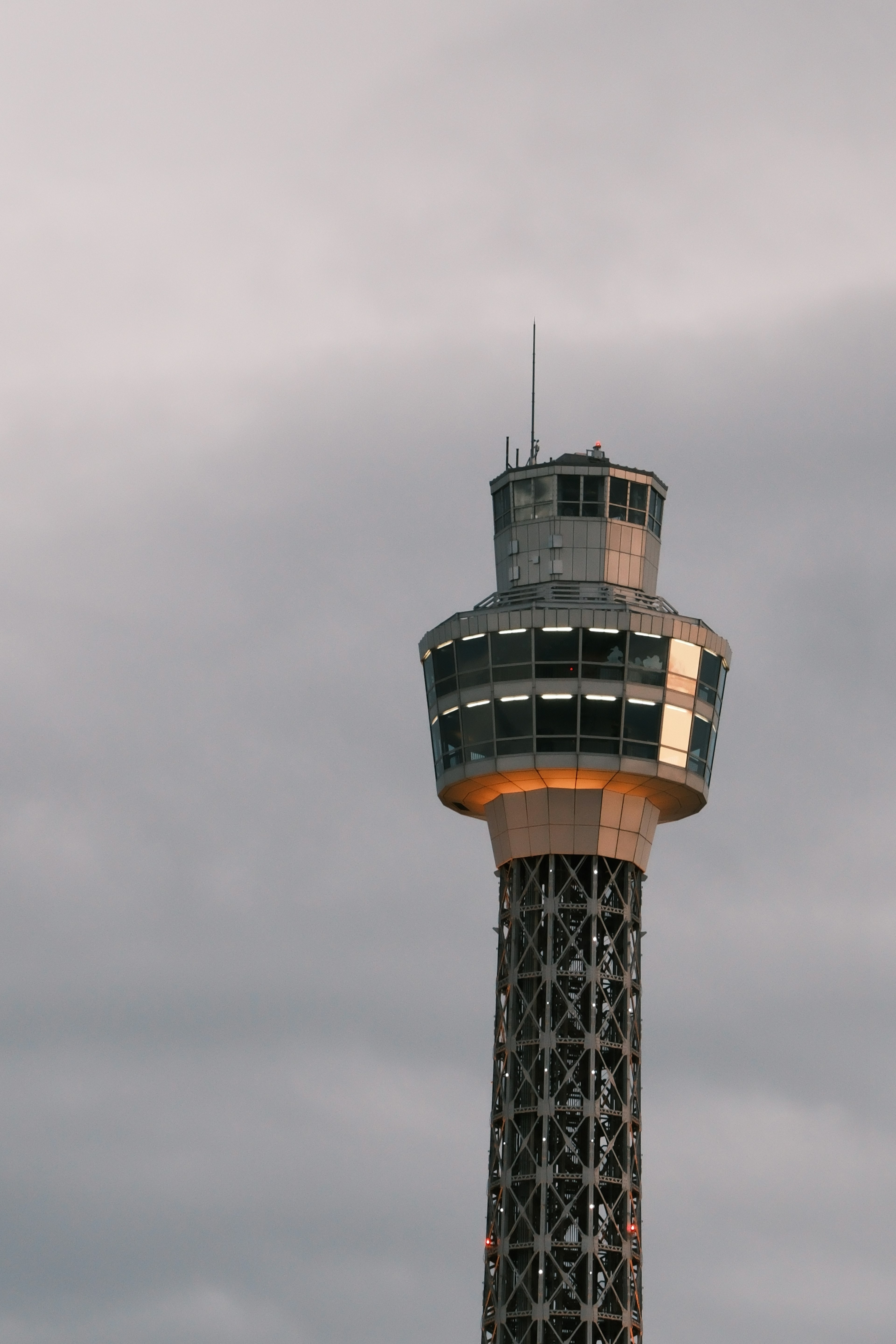 Image of the upper part of an airport control tower against a cloudy sky