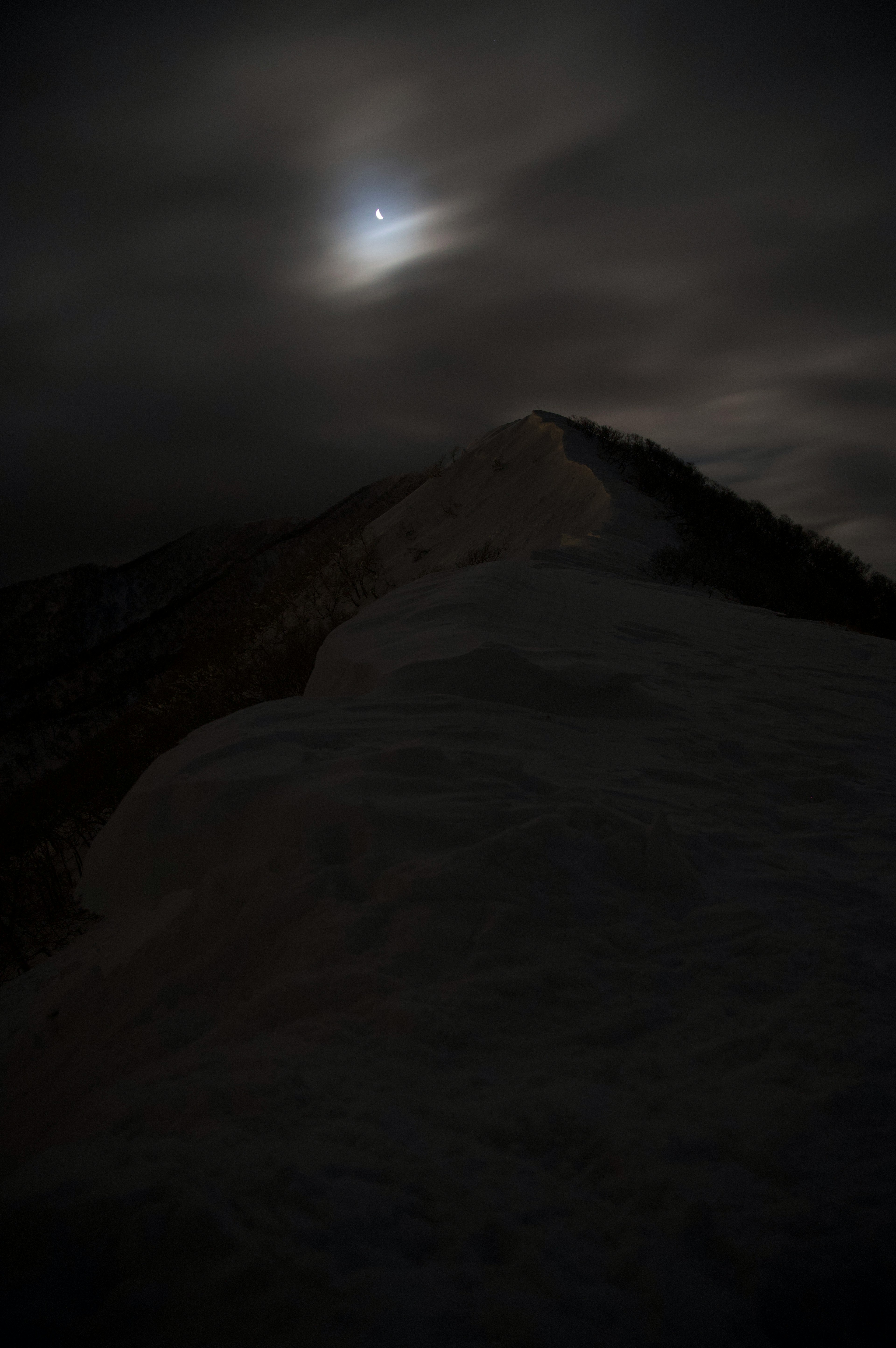 暗い雲に覆われた山の頂上と月