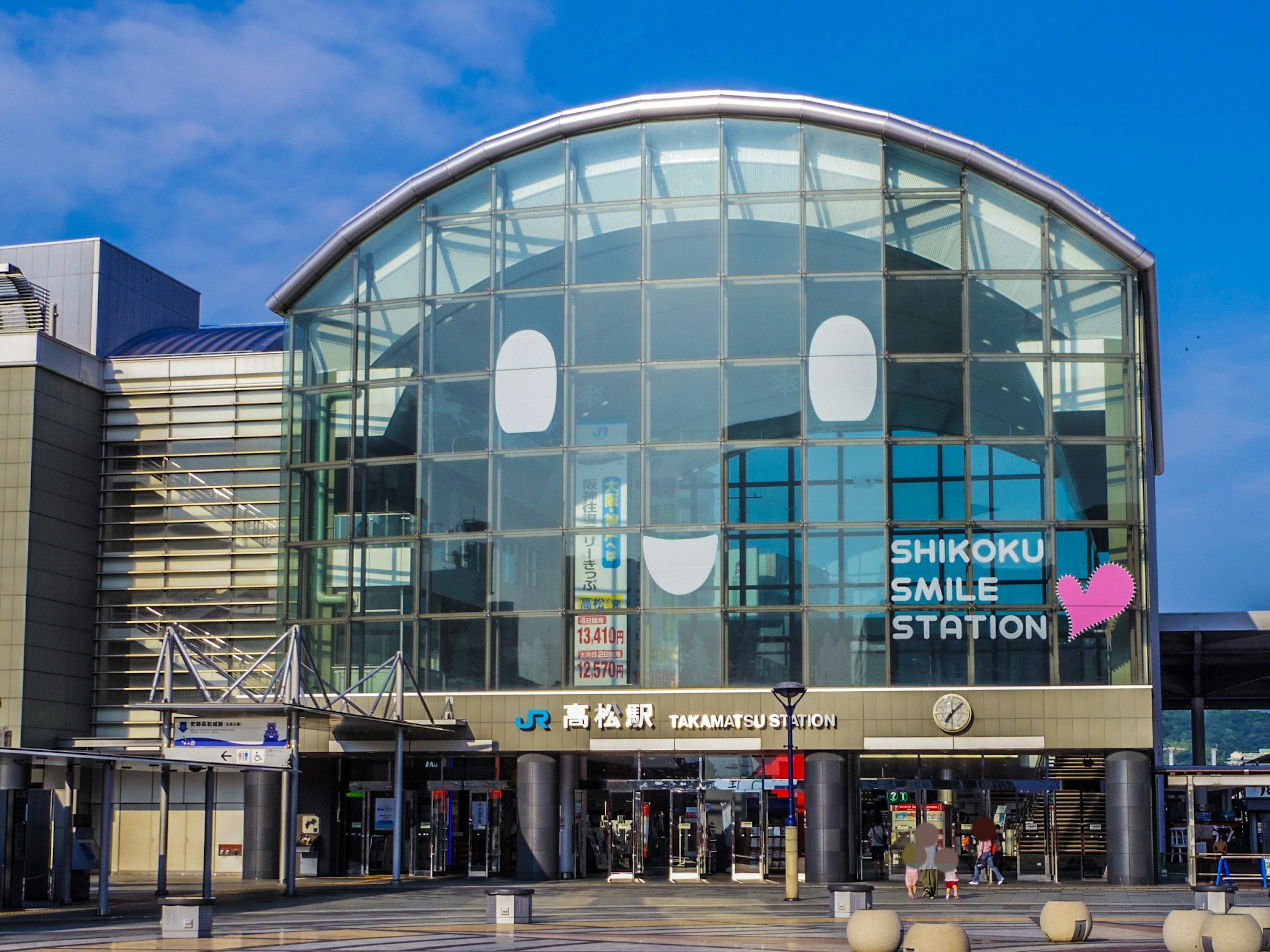 Extérieur de la gare Shikoku Smile avec un bâtiment en verre et un design de visage souriant