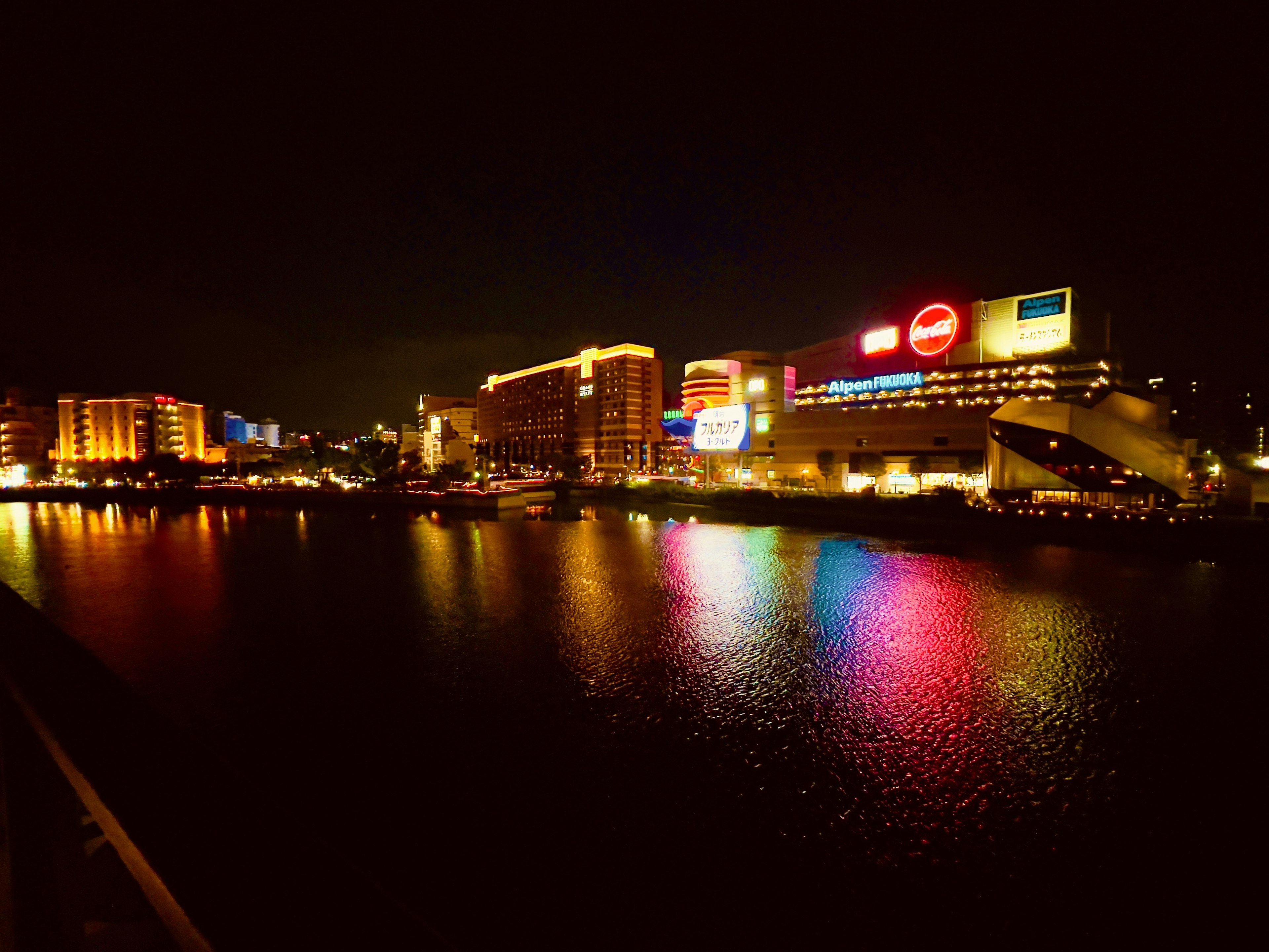 Hermosa vista del río por la noche con edificios iluminados y reflejos coloridos