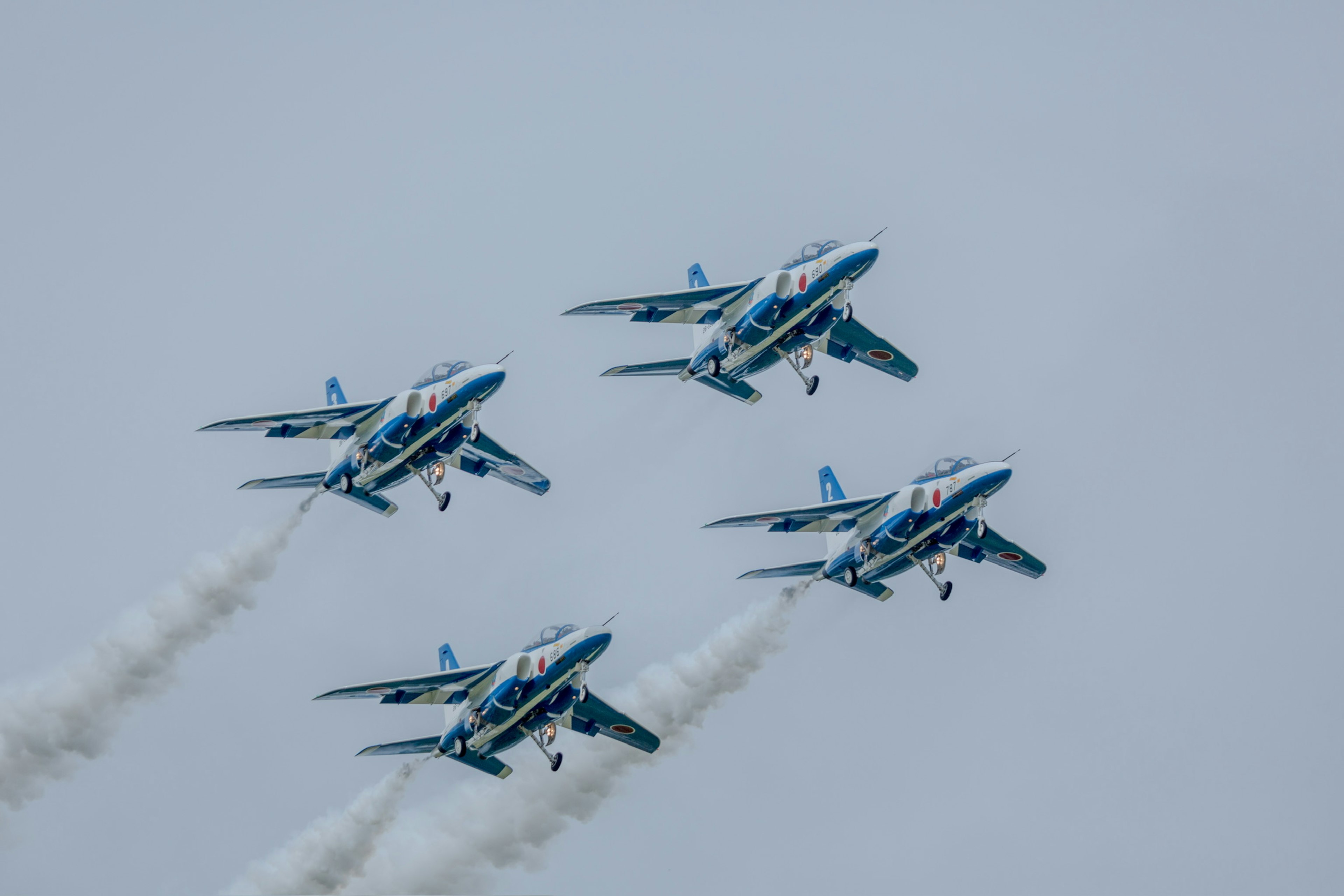 Cuatro aviones azules y blancos volando en formación en el cielo