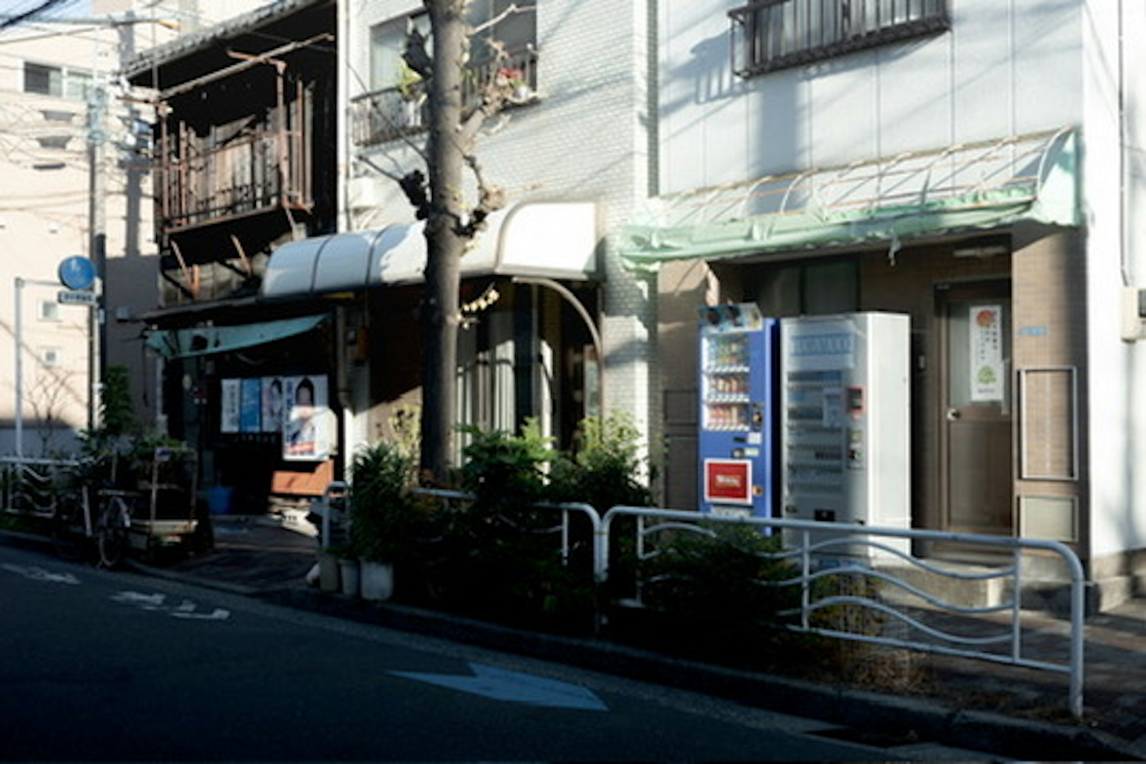 Exterior of a small shop on a quiet street with a vending machine