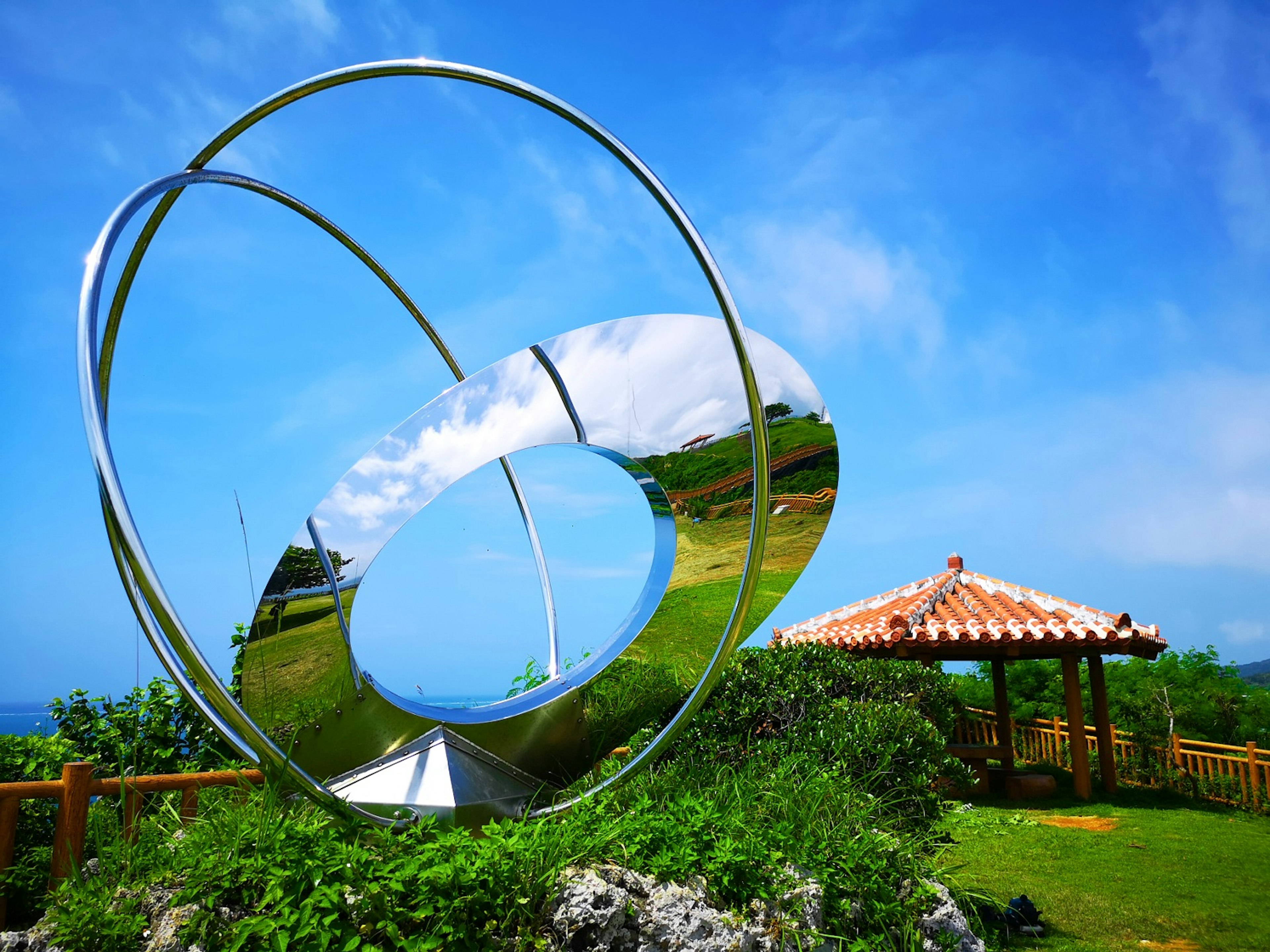 Metal sculpture under blue sky with surrounding landscape