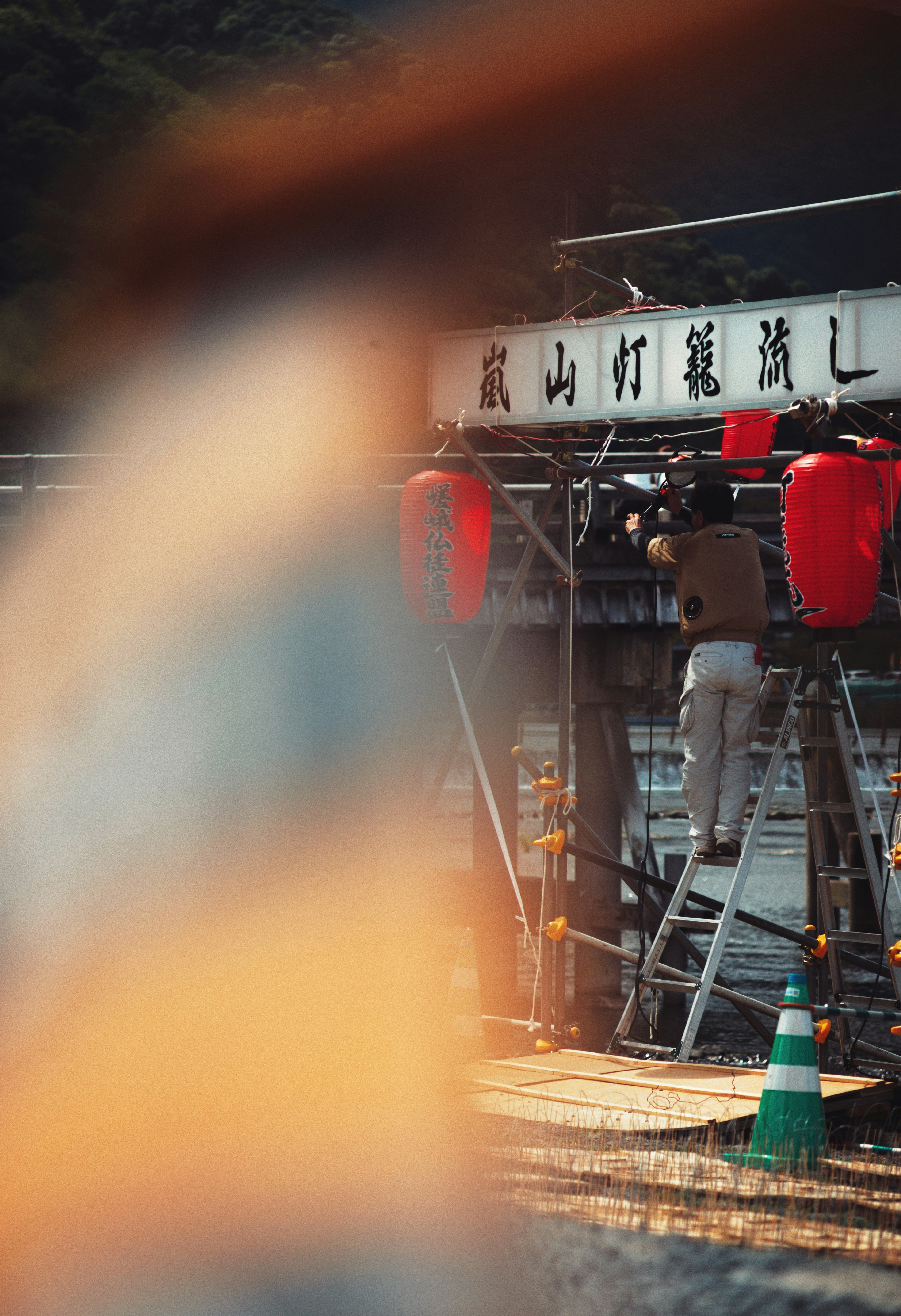 A worker adjusting a sign with red lanterns in the background