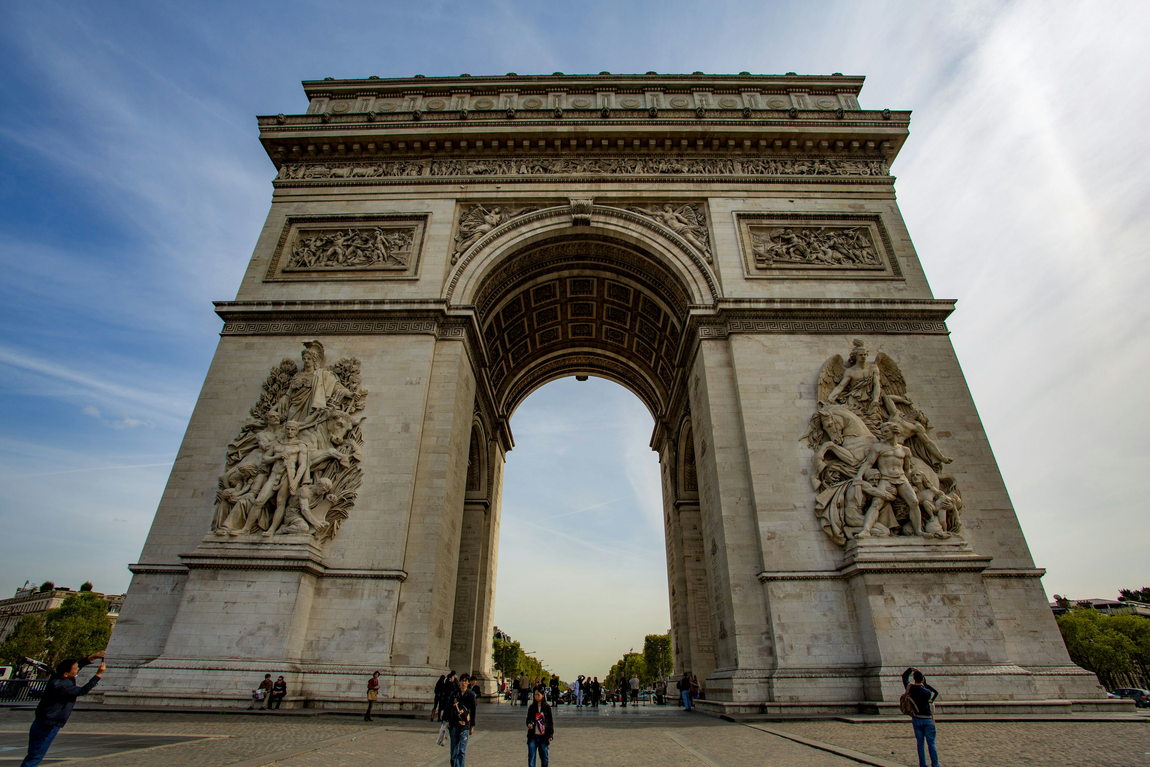 Gambar Arc de Triomphe di Paris diambil dari sudut rendah dengan orang-orang di sekitarnya