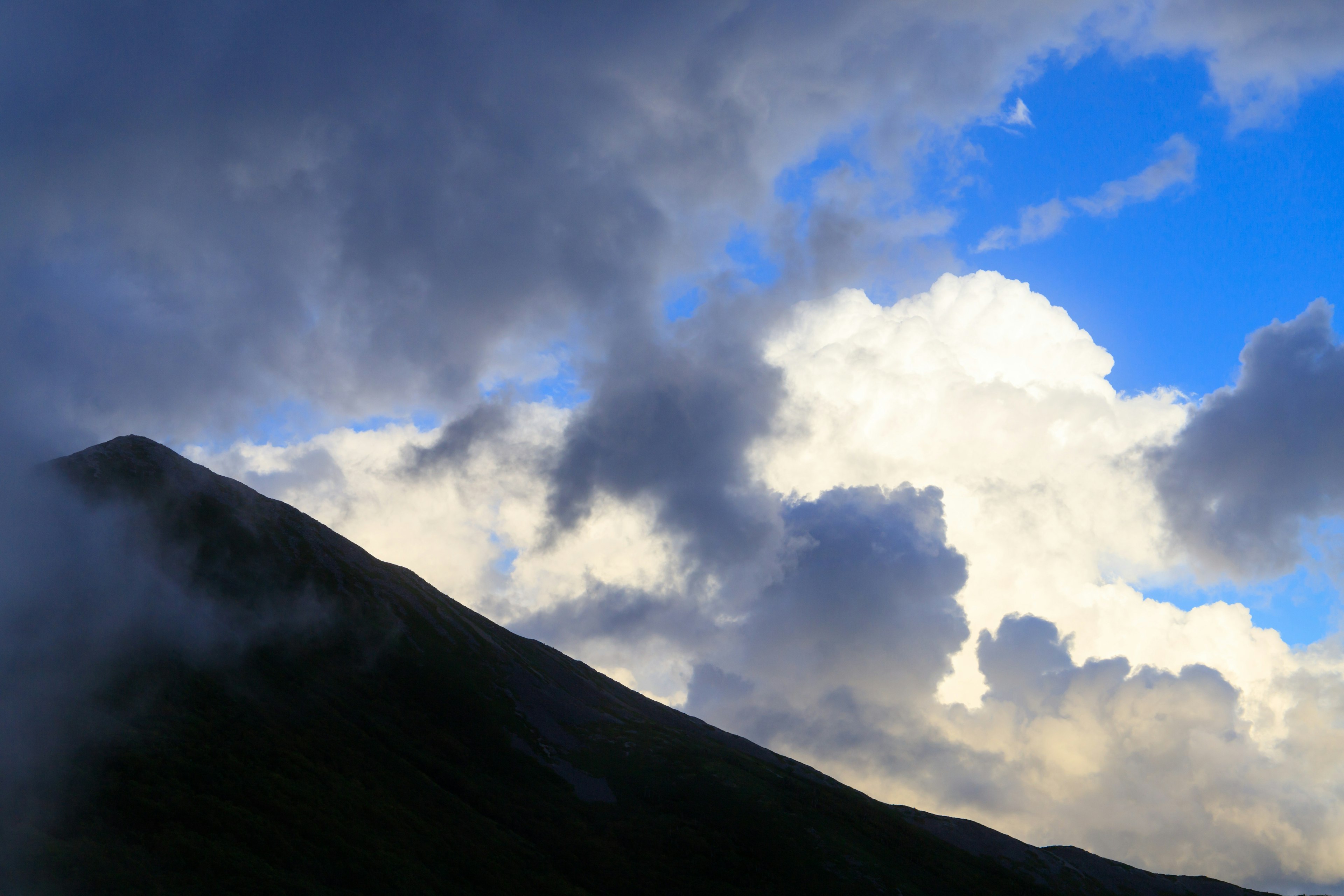 Silhouette eines Berges vor einem blauen Himmel mit Wolken