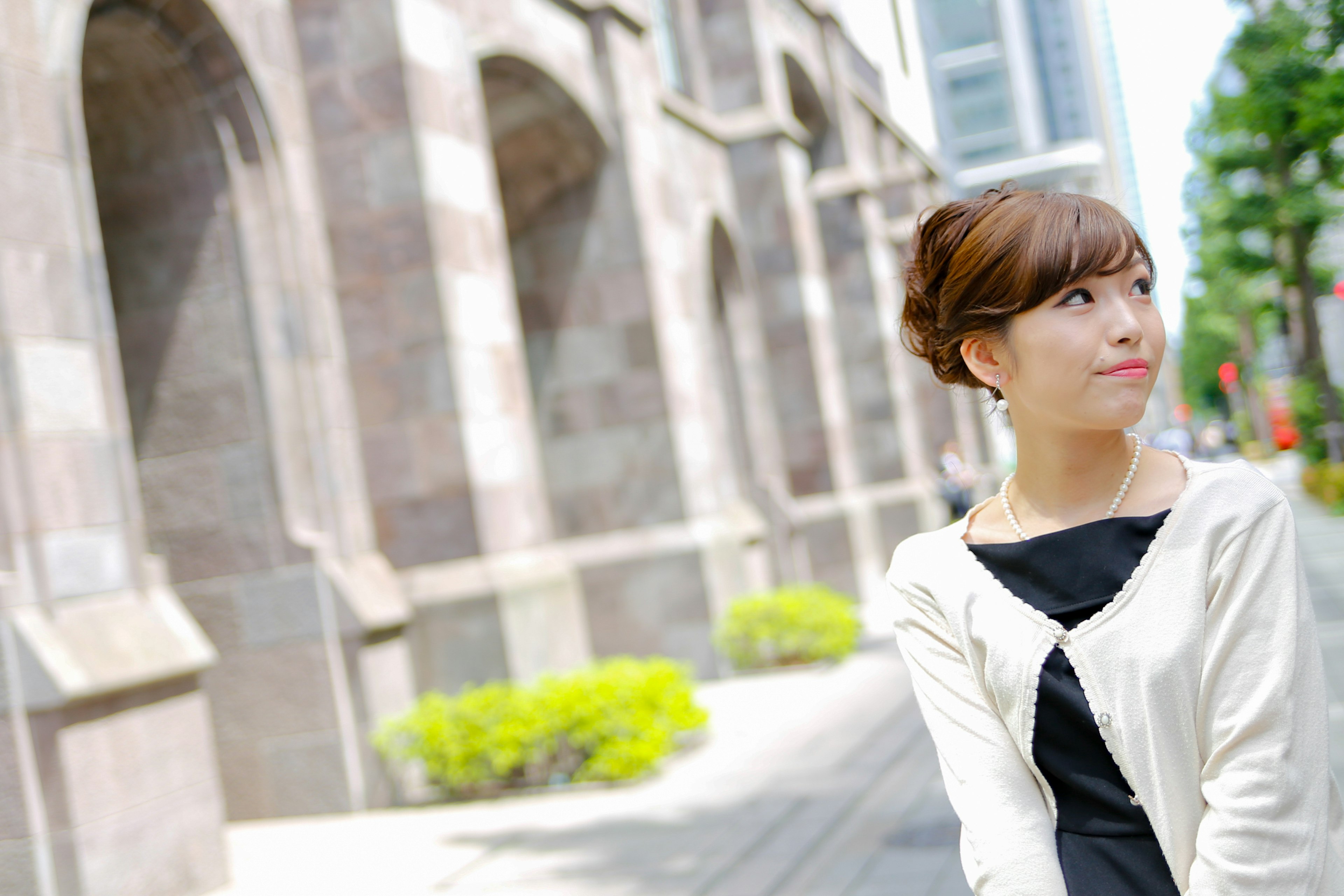 A woman smiling in the city with a stone building in the background