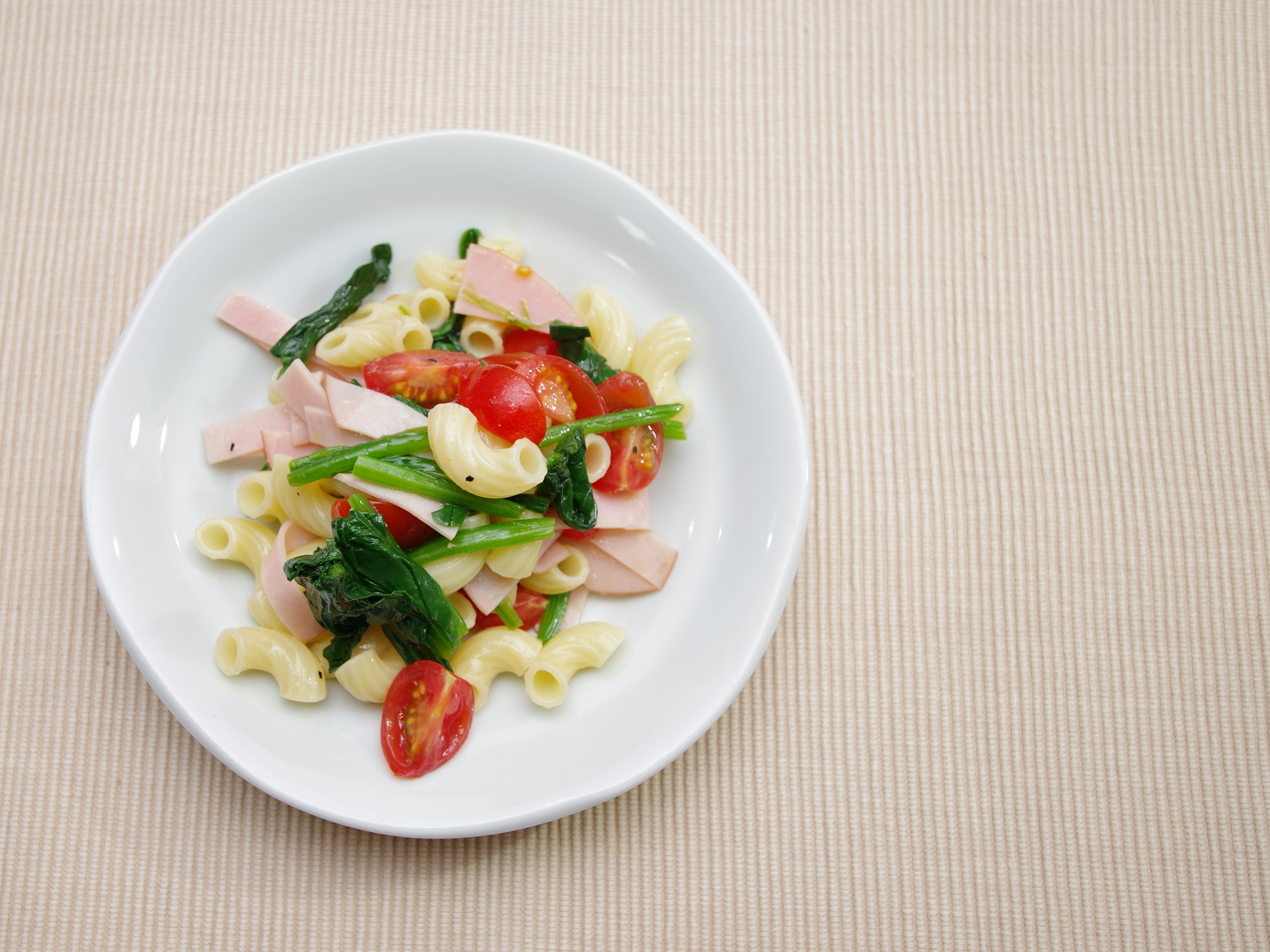 Makkaroni-Salat mit Tomaten und Gemüse auf einem weißen Teller