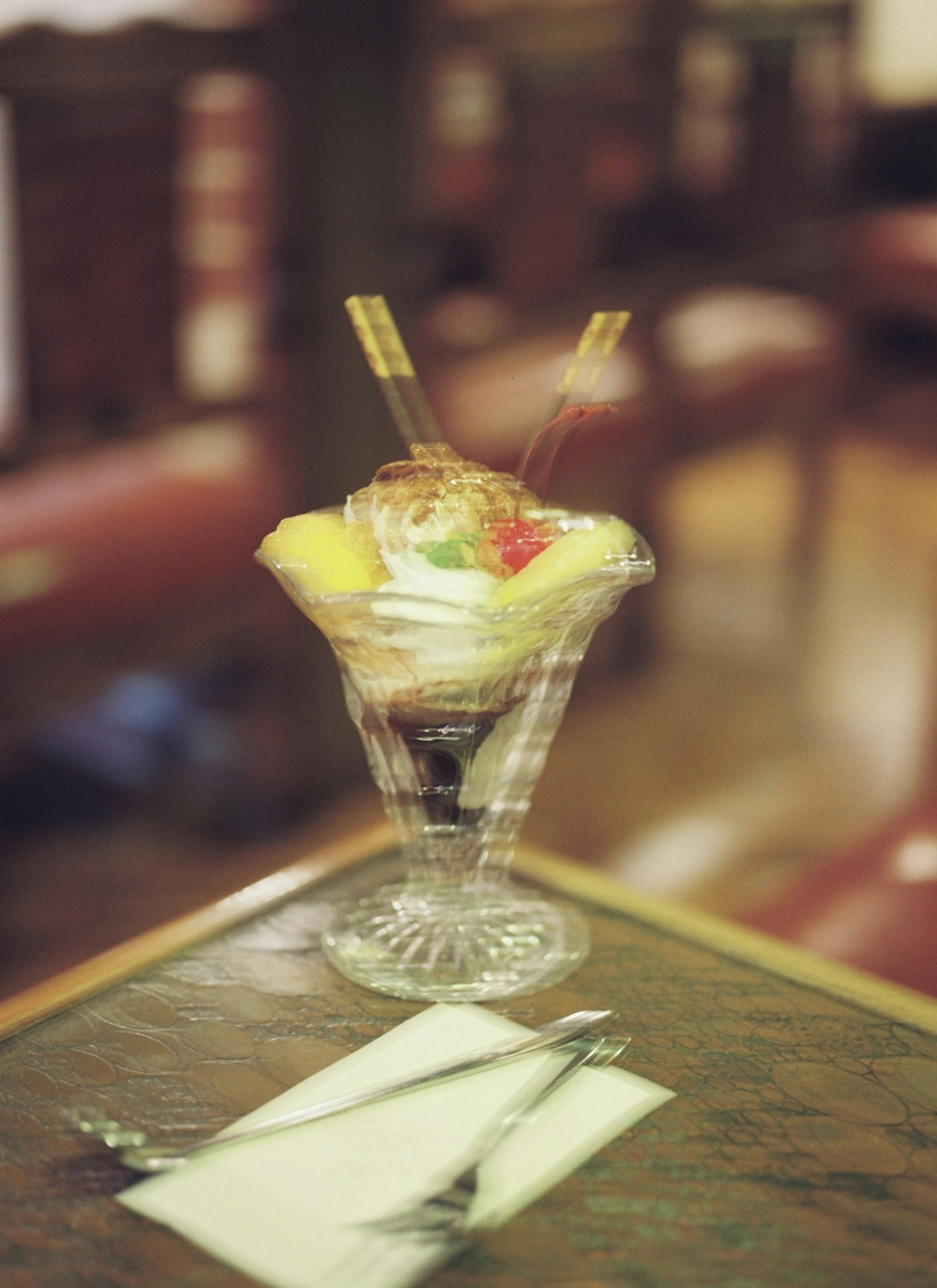 A dessert cup filled with cream and fruits placed on a table