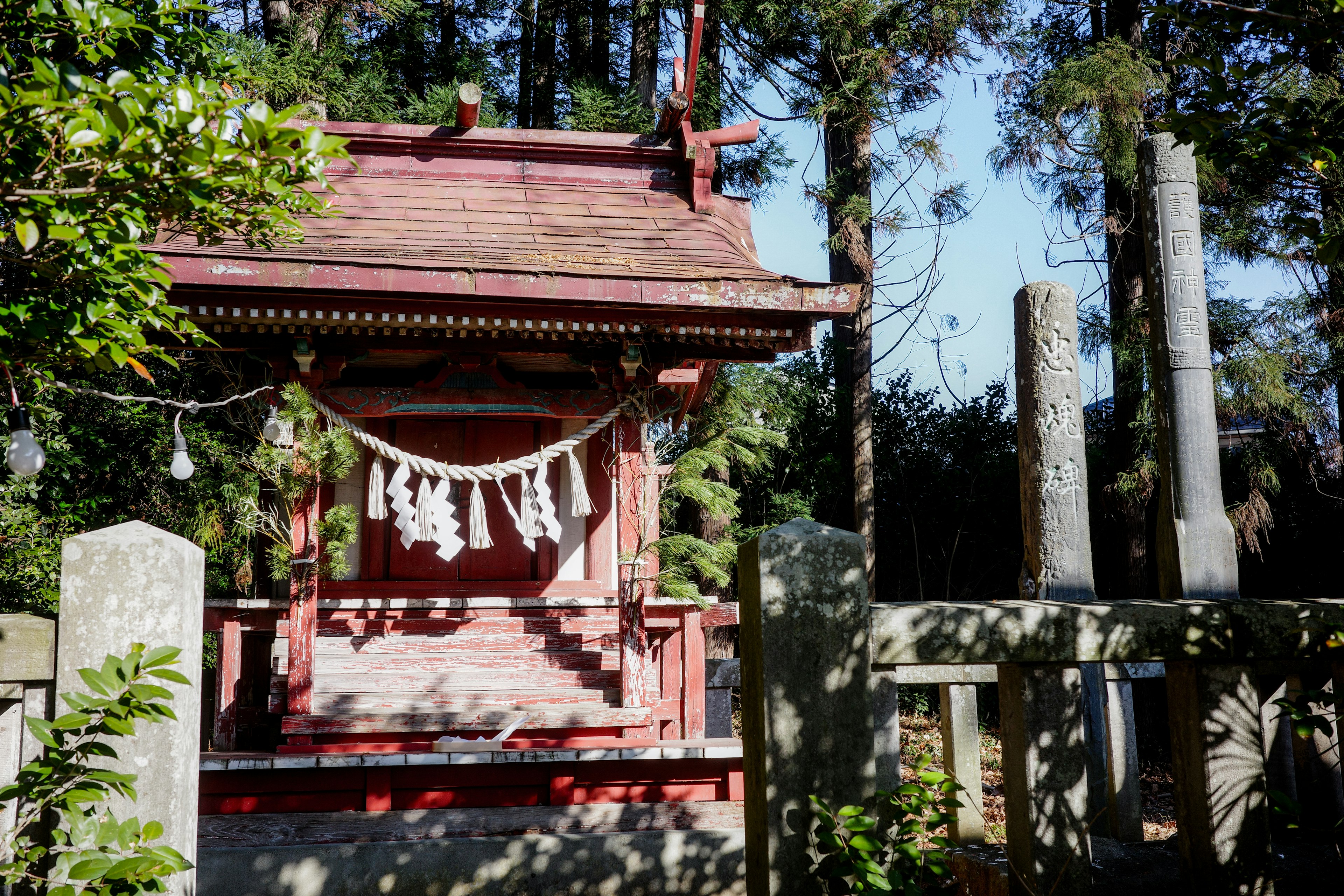 赤い神社の小さな建物と周囲の木々が印象的な風景