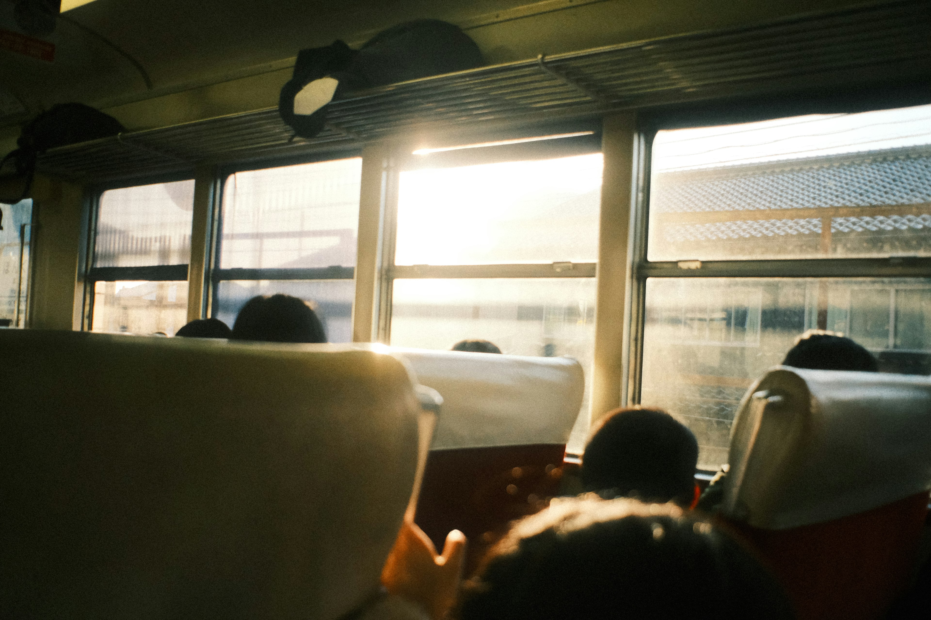 Sunlight streaming through a bus window with passengers visible