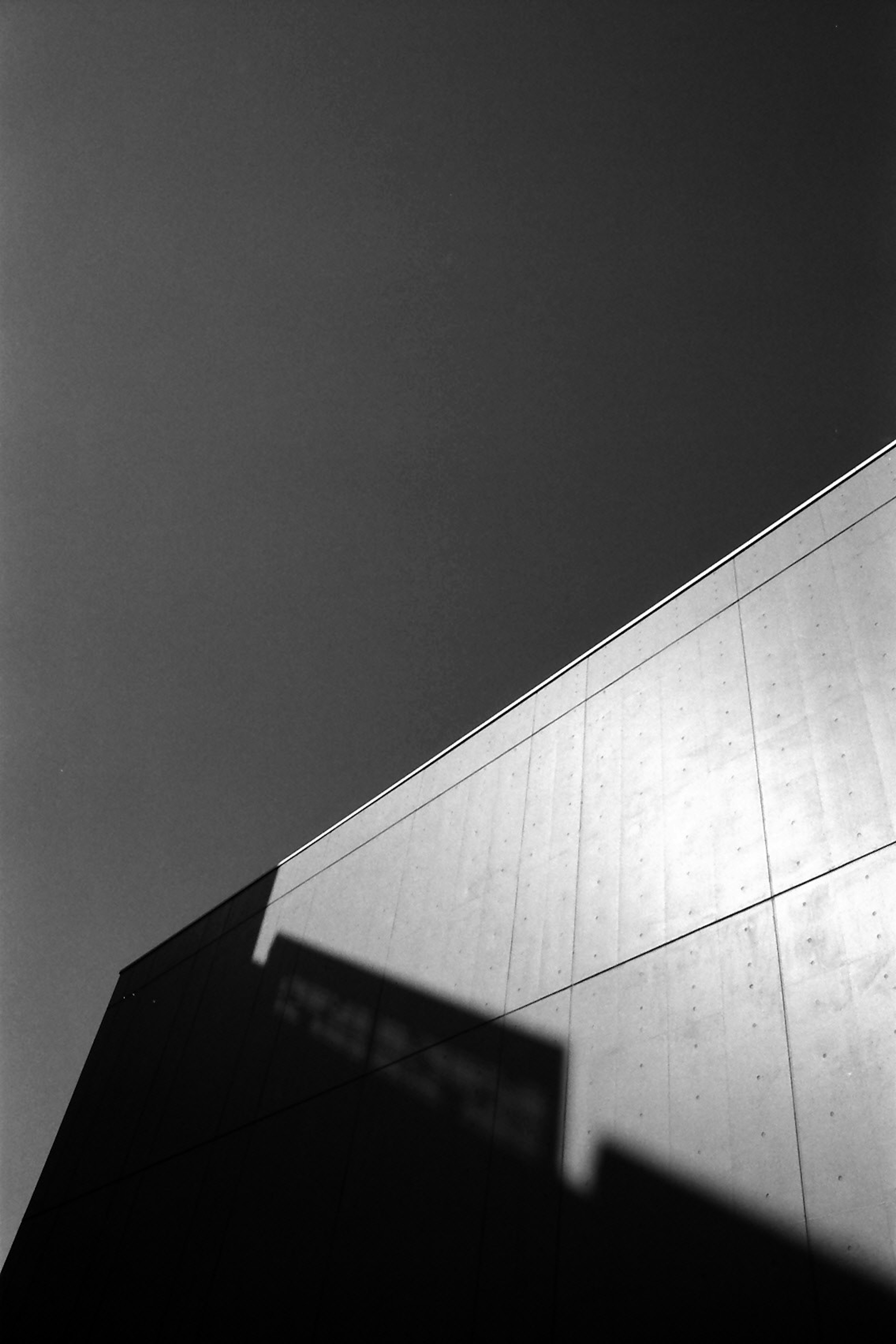 Black and white photograph of a building corner casting a shadow